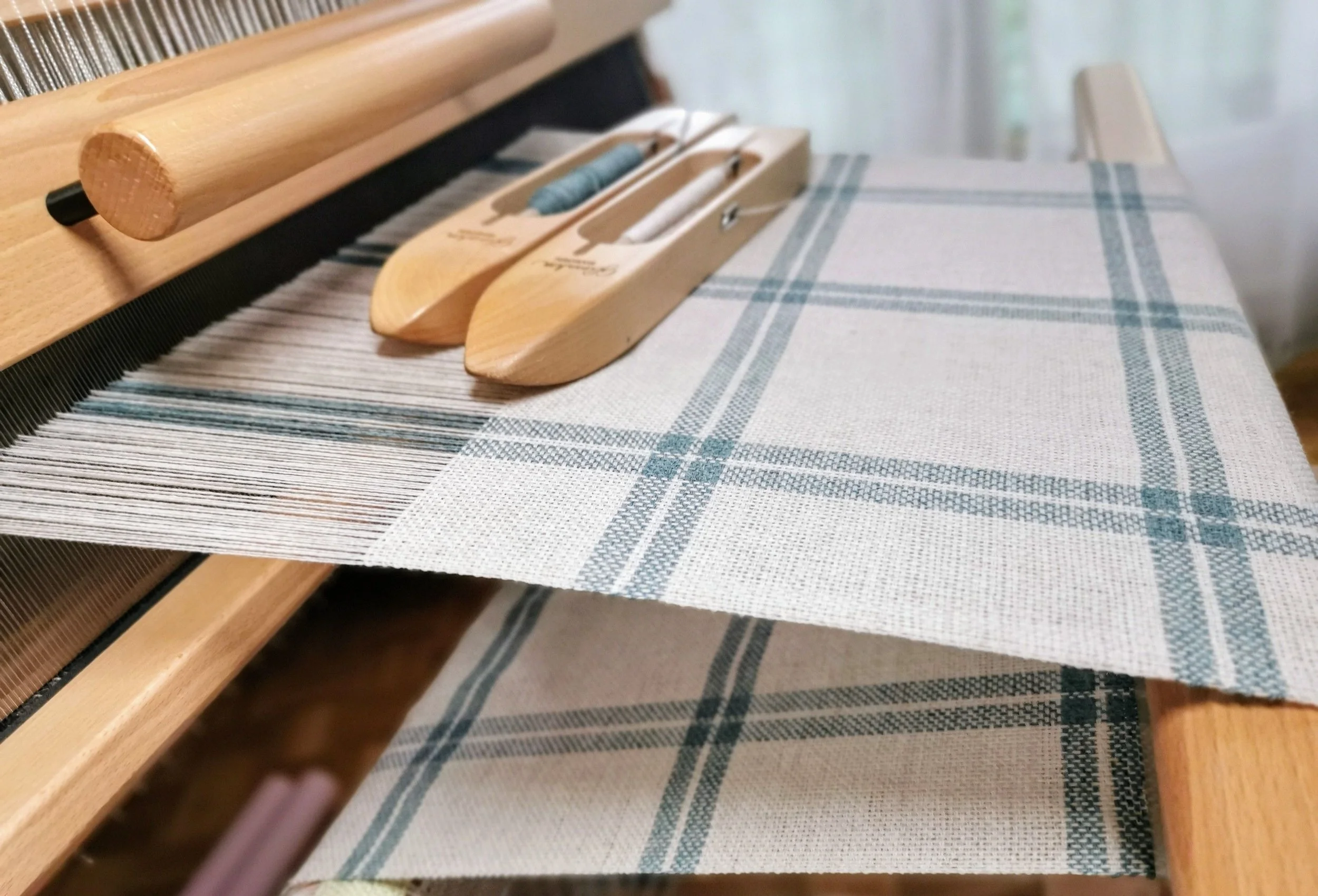Écharpe Jade en cours de tissage sur métier à bras, armure toile en cachemire écru et vert jade, navettes visibles