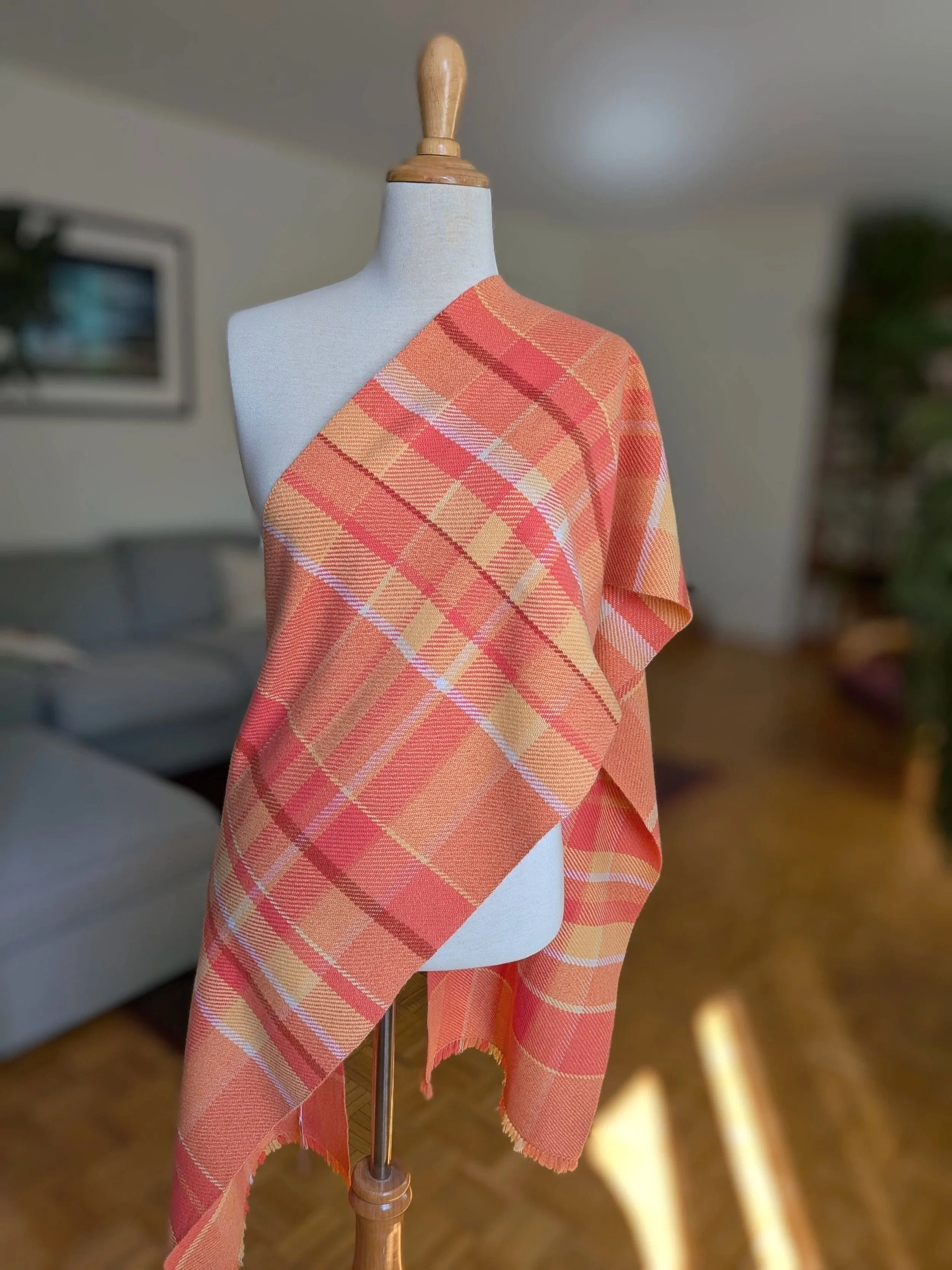Écharpe Mandarine en pur cachemire drapée en diagonale sur l'épaule d'un mannequin, motif de carreaux en nuances d'orange, de corail et de jaune doré