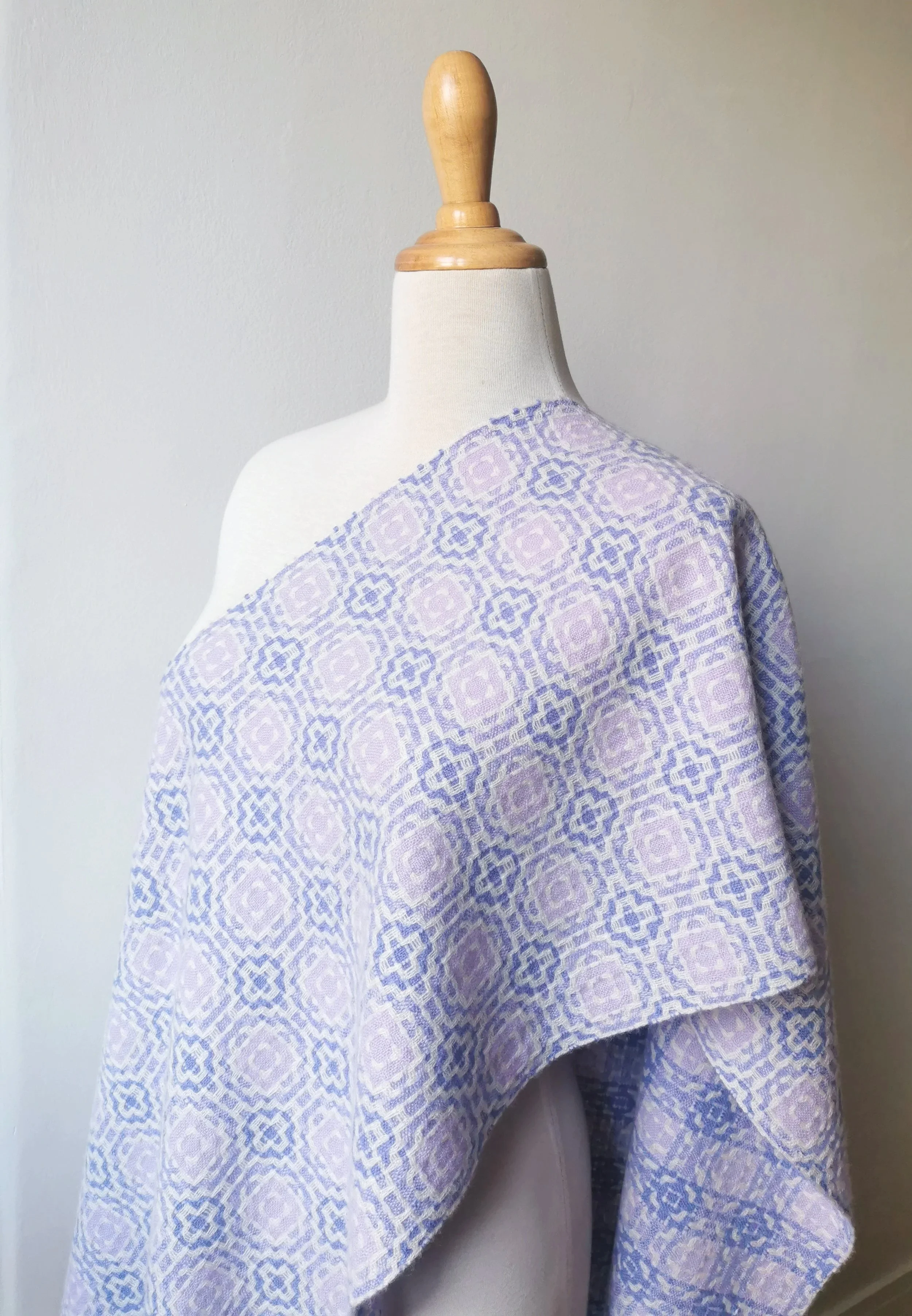 Écharpe Lilas en pur cachemire drapée en diagonale sur l'épaule d'un mannequin, motif géométrique en violet foncé et violet pâle sur fond blanc
