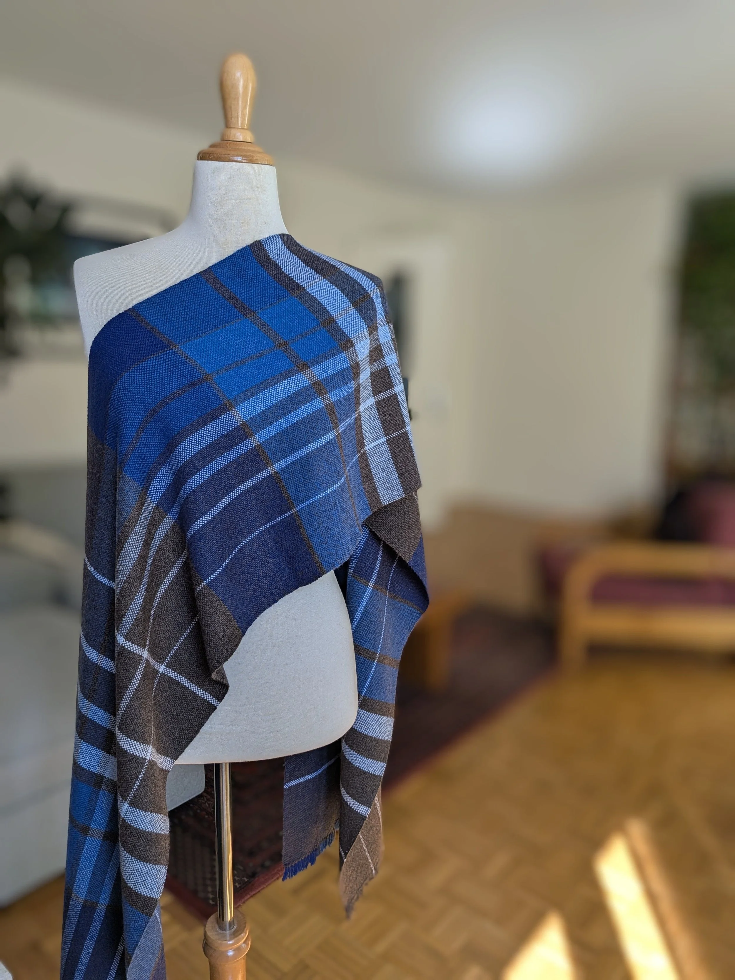 Écharpe Boréal en pur cachemire drapée en diagonale sur l'épaule d'un mannequin, motif de carreaux en camaïeu de bleus, brun profond et blanc