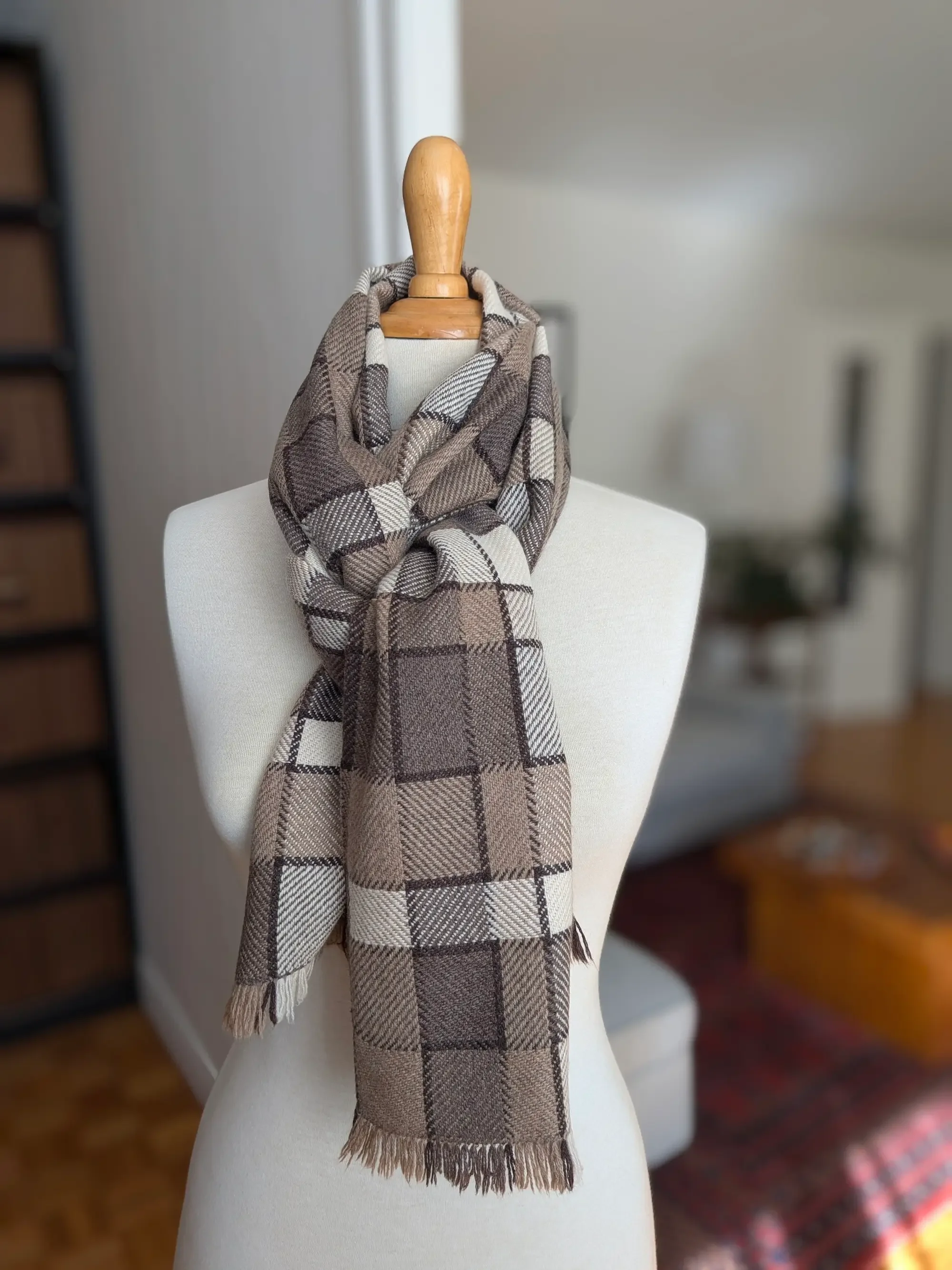 Écharpe Agate en pur cachemire nouée autour du cou d’un mannequin et retombant sur le devant, carreaux taupe, bruns et blanc cassé