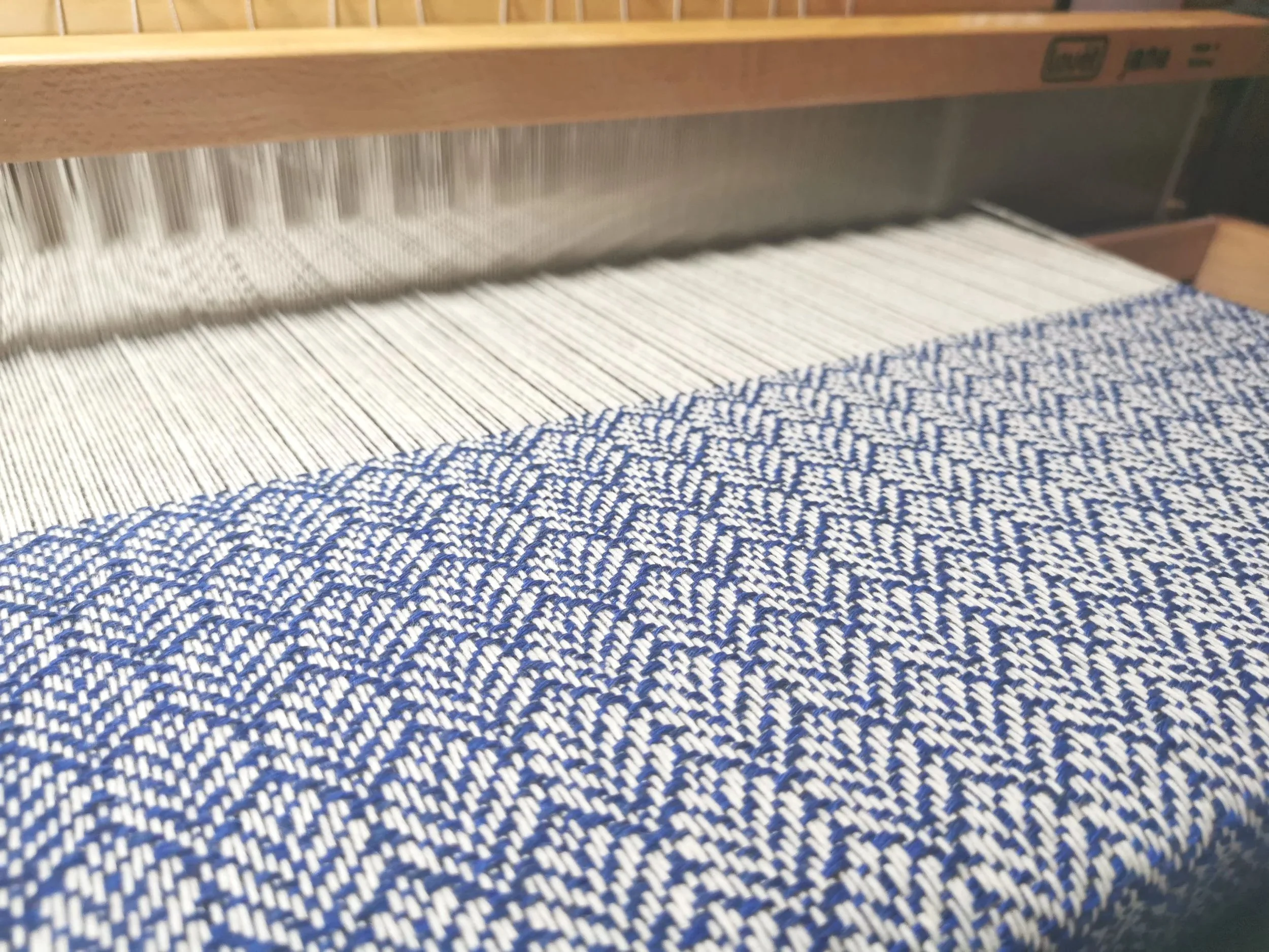 Écharpe Rythme en cours de tissage sur métier à bras, motif géométrique en cachemire bleu profond