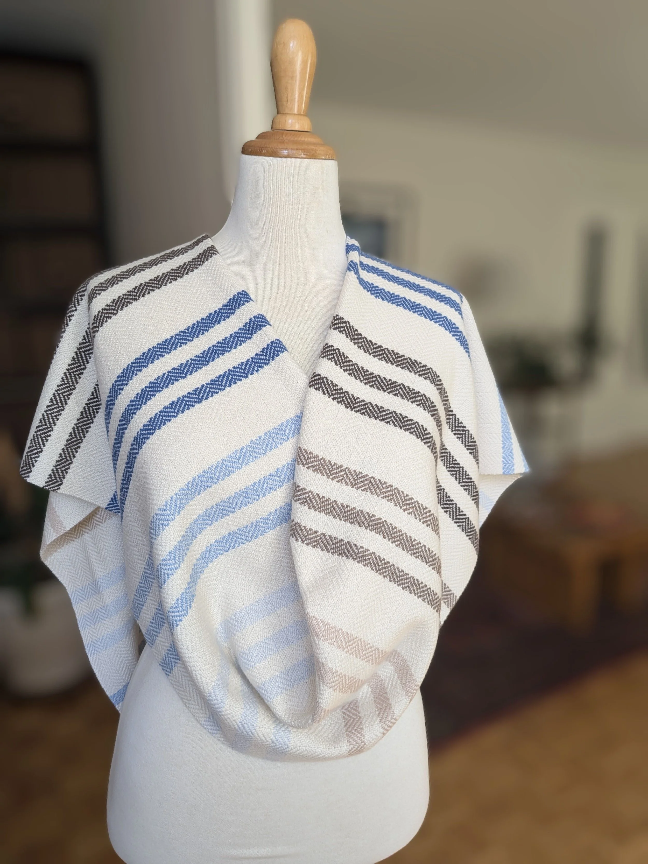 Écharpe Rivage en pur cachemire drapée sur les épaules et croisée devant un mannequin, rayures en chevrons bleu marine, bleu clair et brun sur fond écru