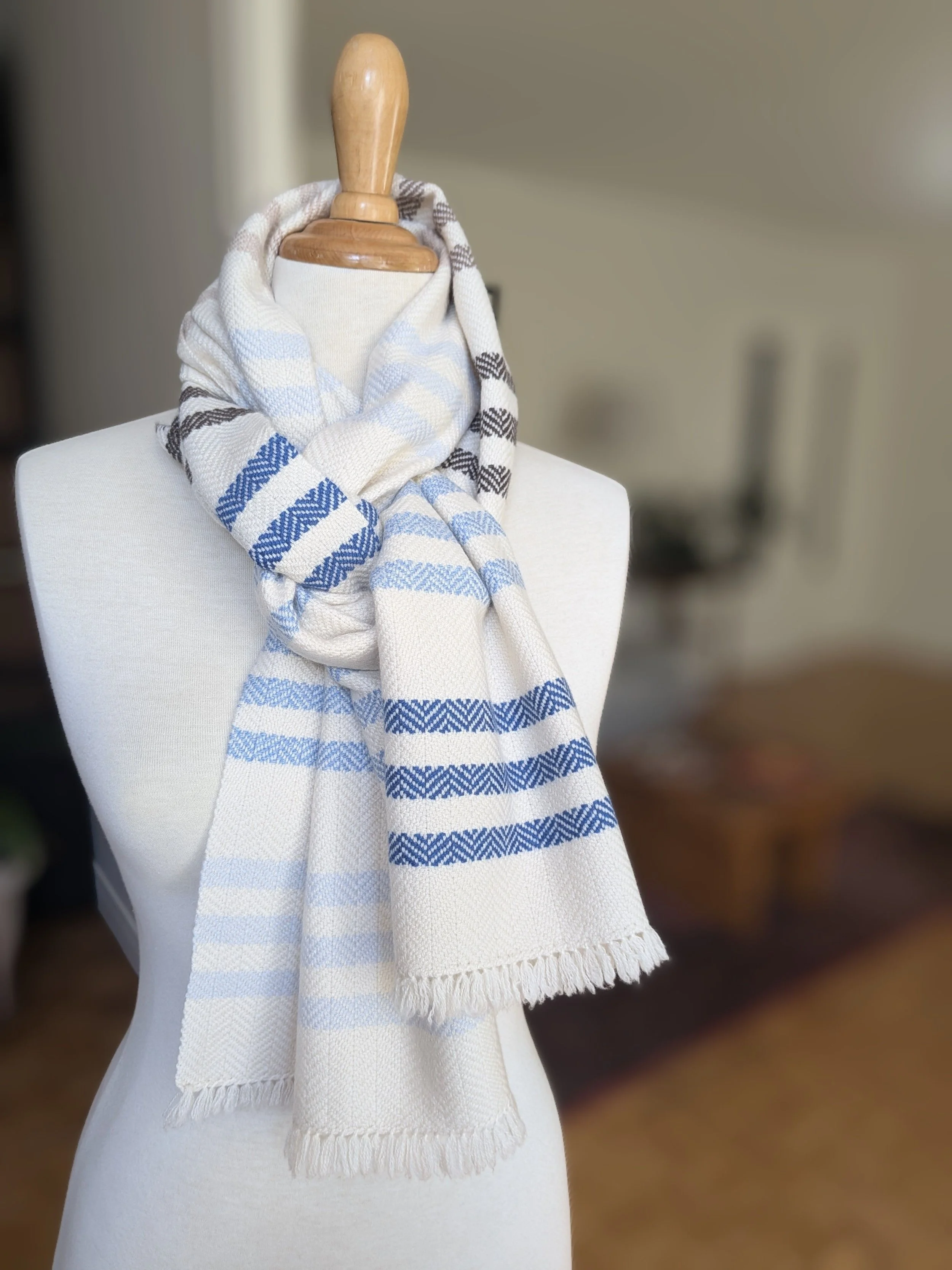 Écharpe Rivage en pur cachemire nouée autour du cou d'un mannequin, rayures en chevrons bleu marine et bleu clair sur fond écru, courtes franges libres en bas