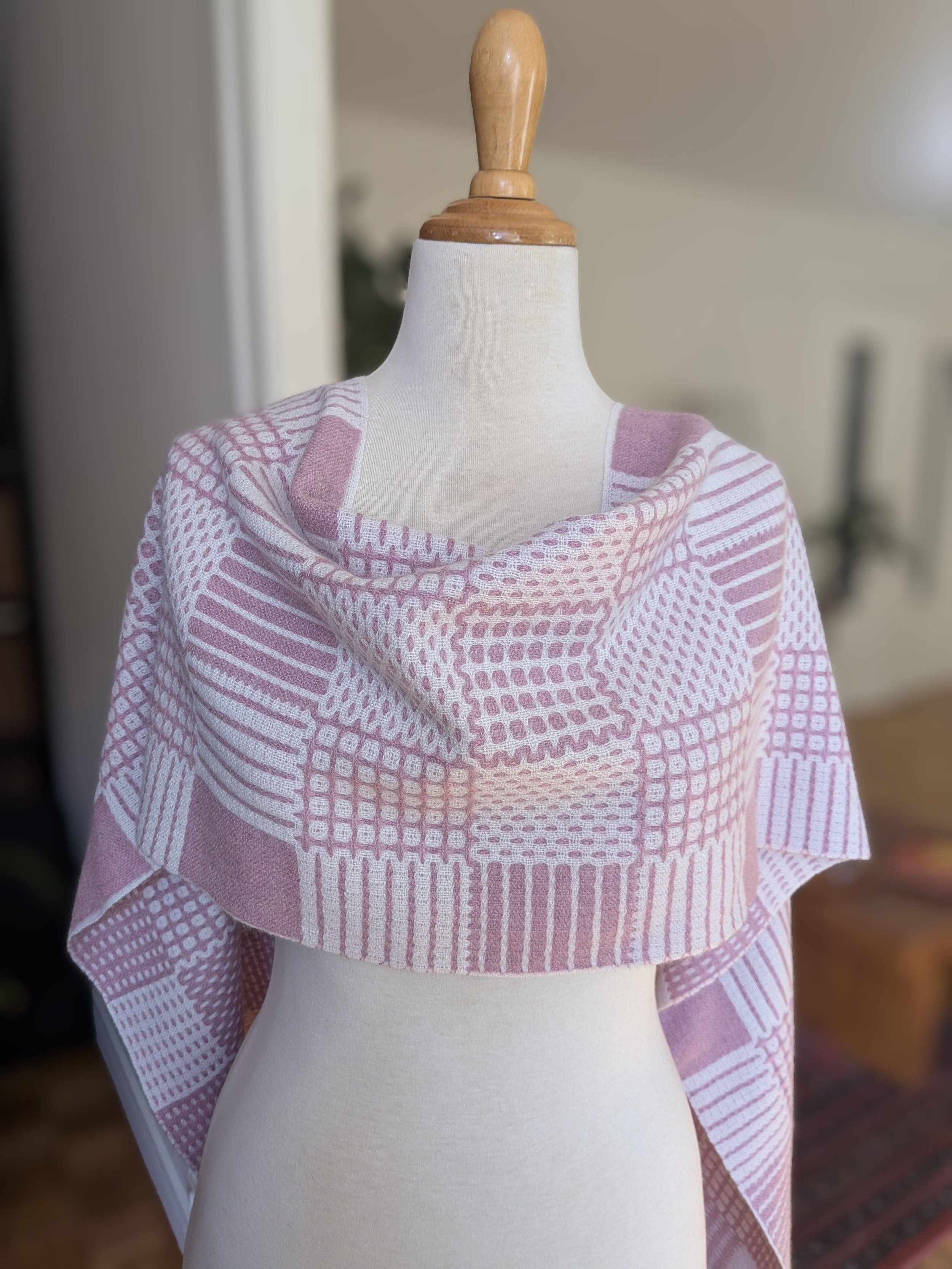 Écharpe Variation poudrée en pur cachemire drapée en châle sur les épaules d'un mannequin : carreaux, pois, rayures et un bloc uni en rose chiné et blanc