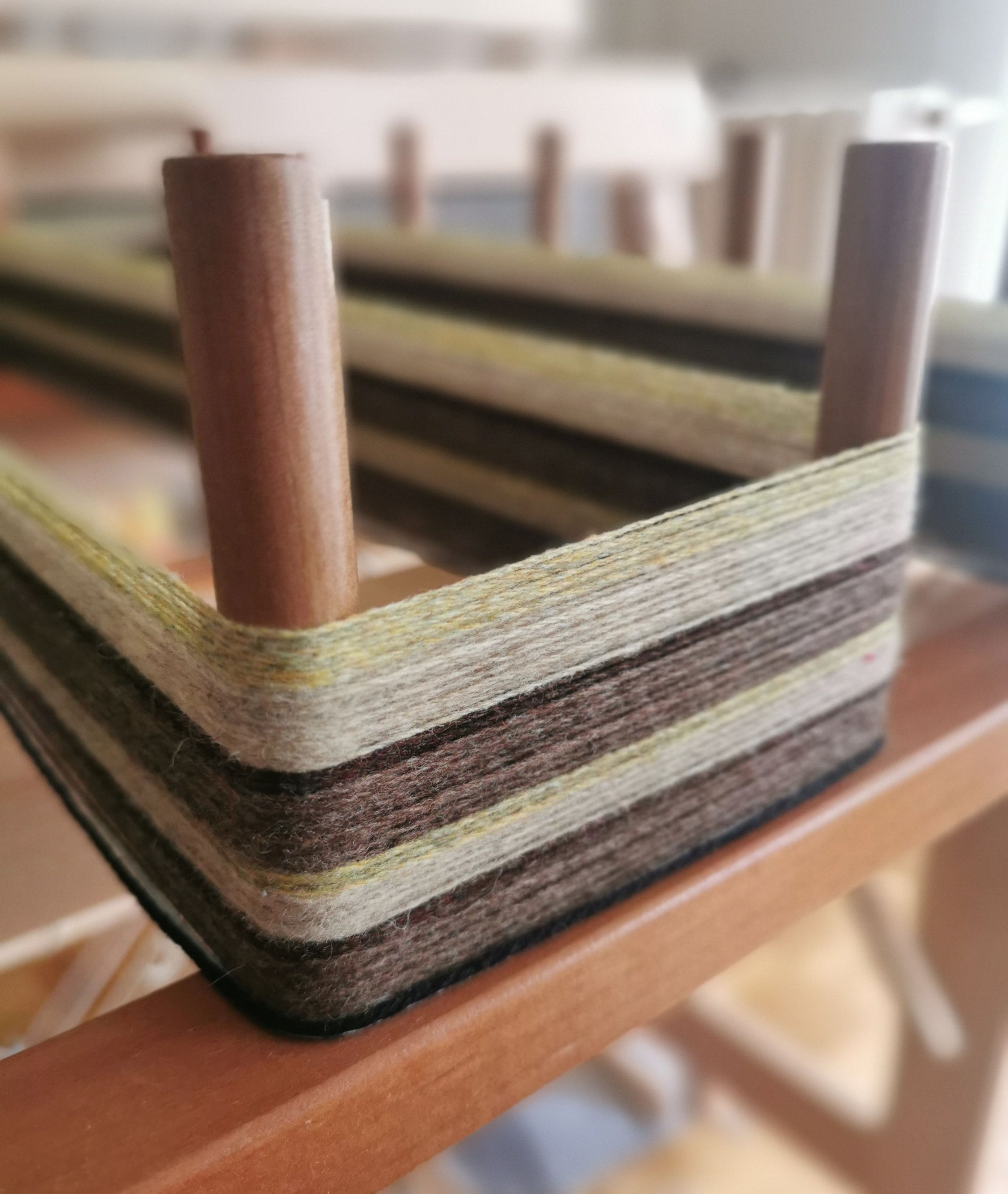 Un organisateur en feutre de différentes couleurs avec des poteaux en bois, posé sur une surface en bois.