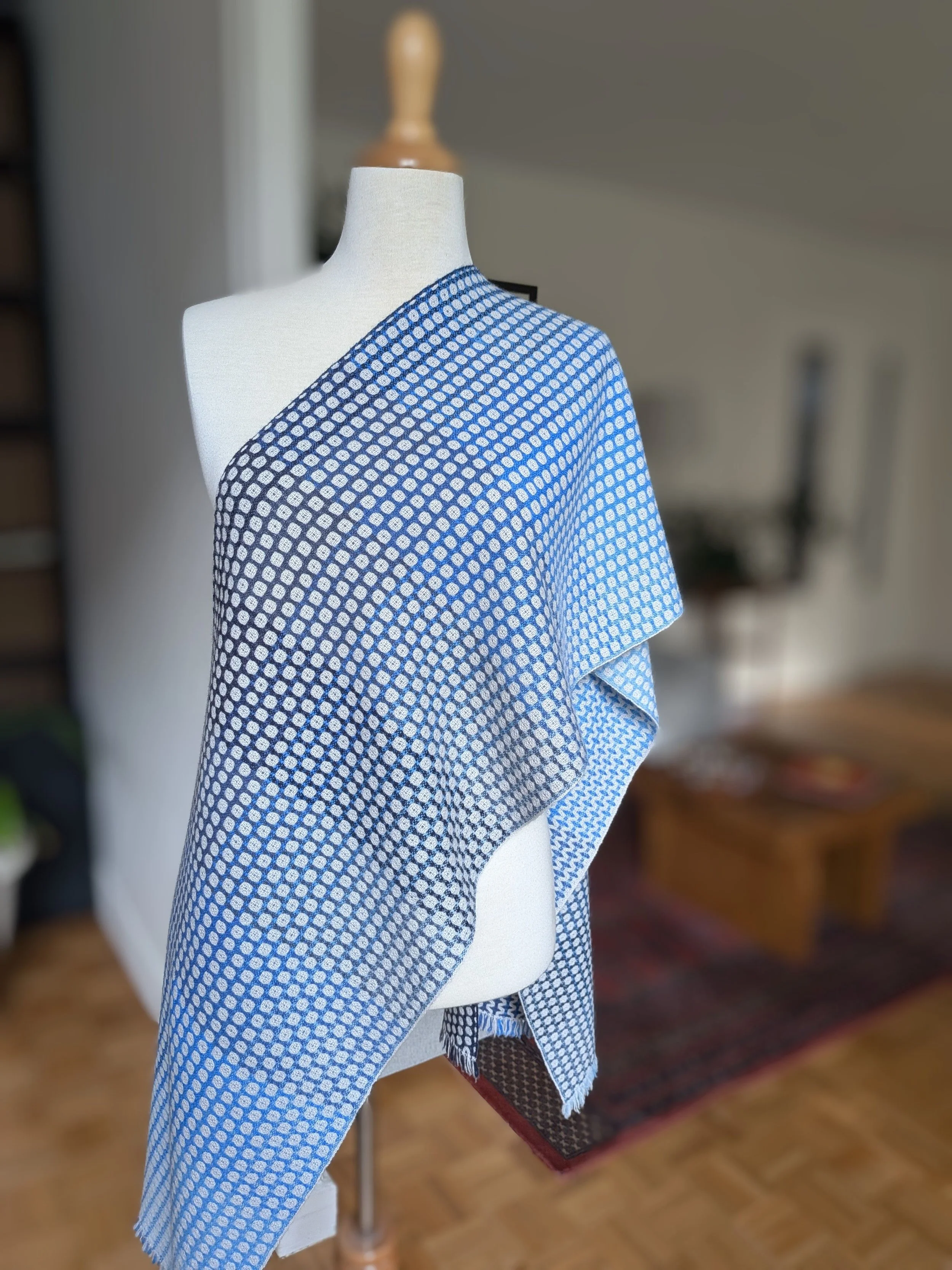 Écharpe Outrebleu en pur cachemire drapée en diagonale sur l'épaule d'un mannequin, face à petits carrés en dégradé de bleu marine à bleu clair