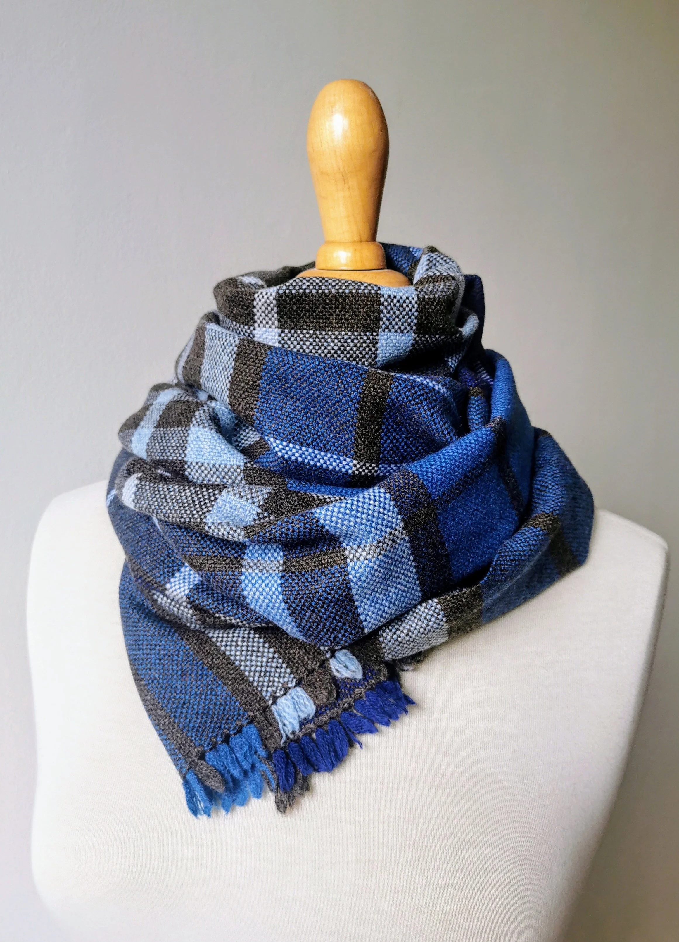 Foulard en tissu à carreaux bleu, noir, gris enroulé autour d'une poupée mannequin en bois