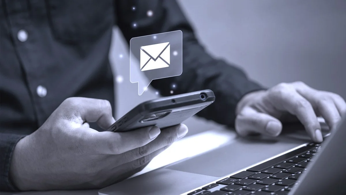 Person using a smartphone with a messaging app, with an email icon notification above the phone.
