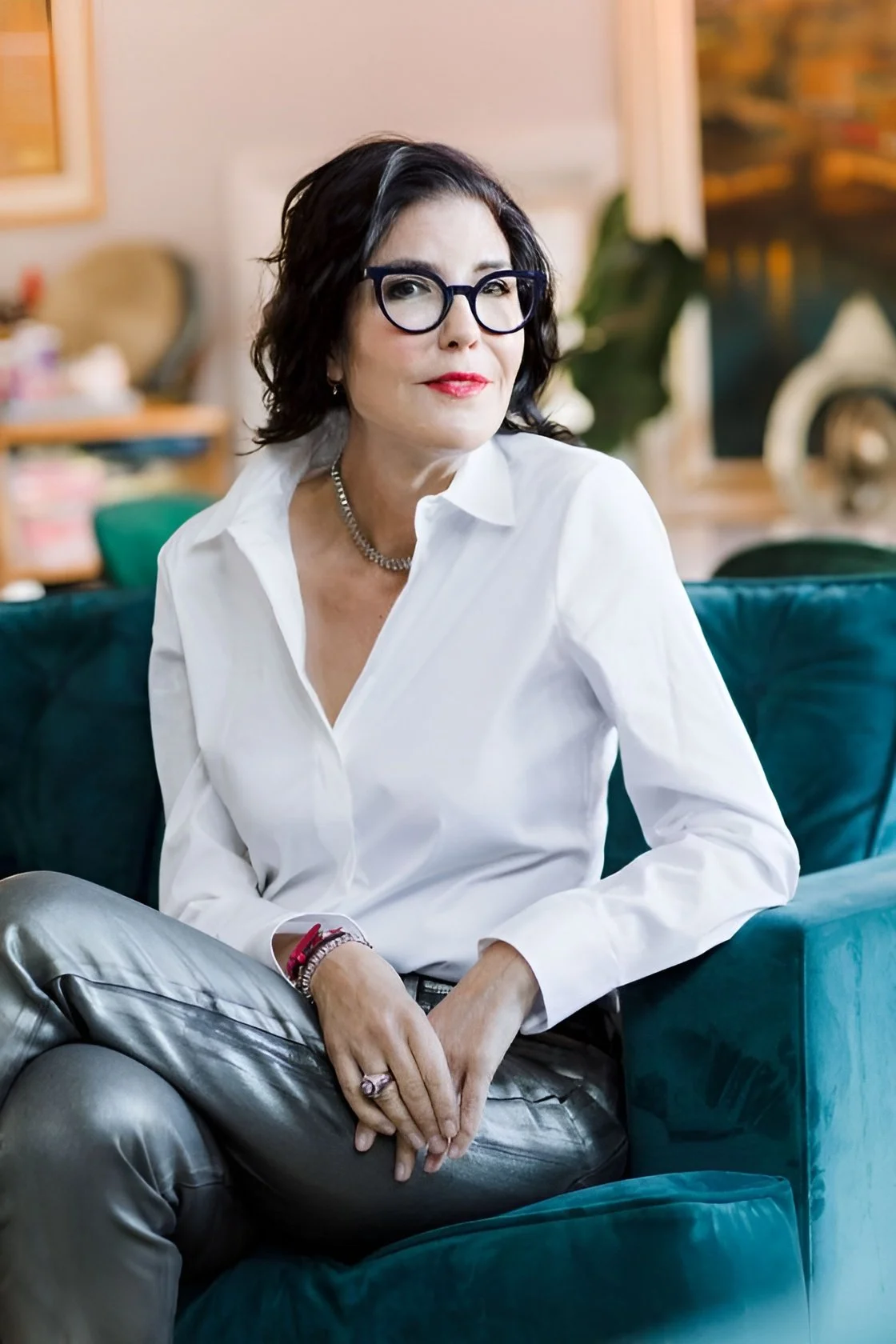 Tina Fordham sitting on a teal sofa in a colourful room.