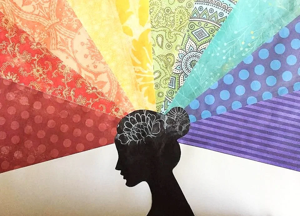 Silhouette of a woman's head with a brain in her hair, from which colorful patterned sections radiate outward.