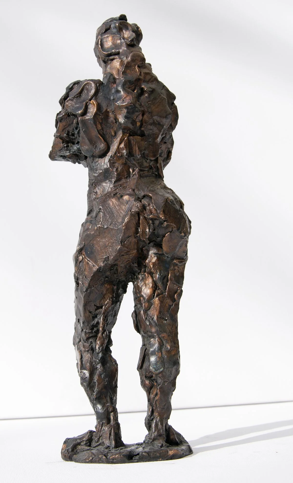 Eine Bronzeskulptur einer stehenden weiblichen Figur mit lockigem Haar, dargestellt in einem abstrakten, strukturierten Stil.
