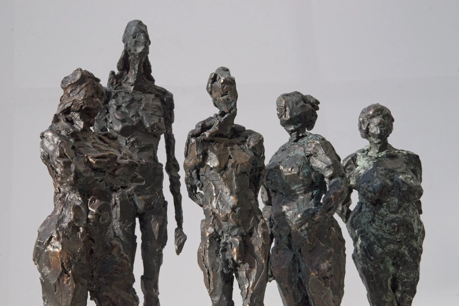 Bronzeskulptur von fünf Frauen, die in einer Reihe stehen, wobei die größte Frau links und die kleinste rechts steht, im Stil der modernen Kunst.
