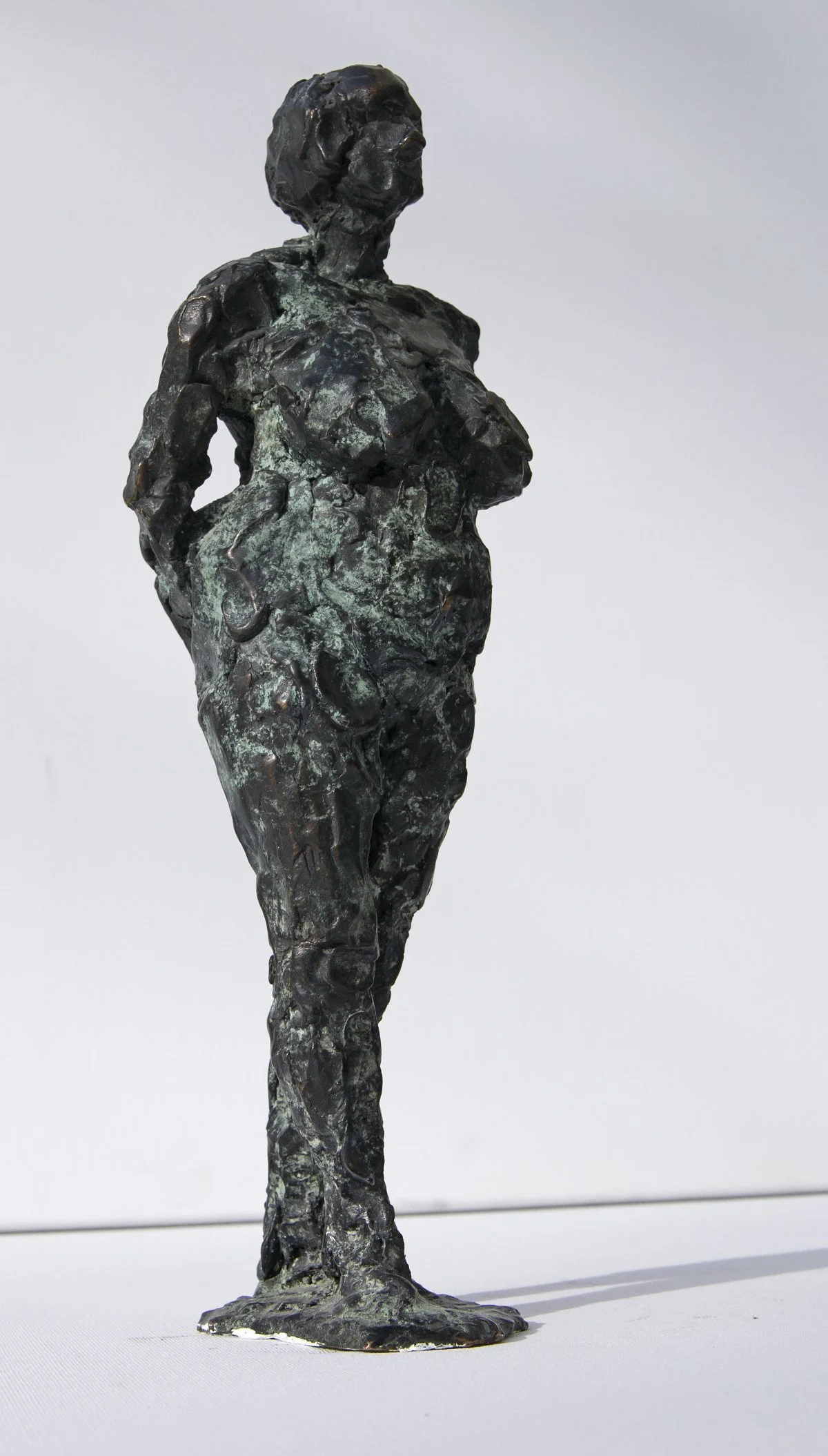 Skulptur einer schwangeren Frau, die mit hinter dem Rücken verschränkten Händen und leicht abgewandtem Kopf dasteht.
