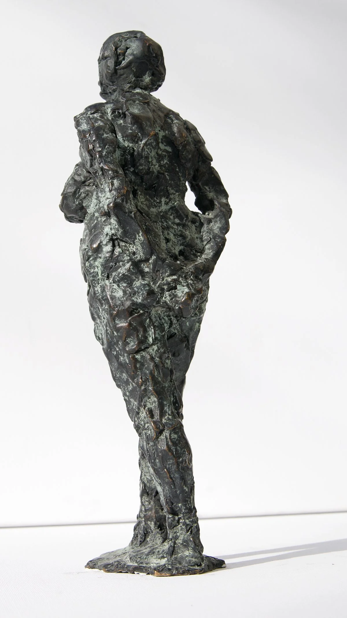 Metallskulptur einer Person mit verschränkten Armen, ausgeführt in einem abstrakten, grob strukturierten Stil.
