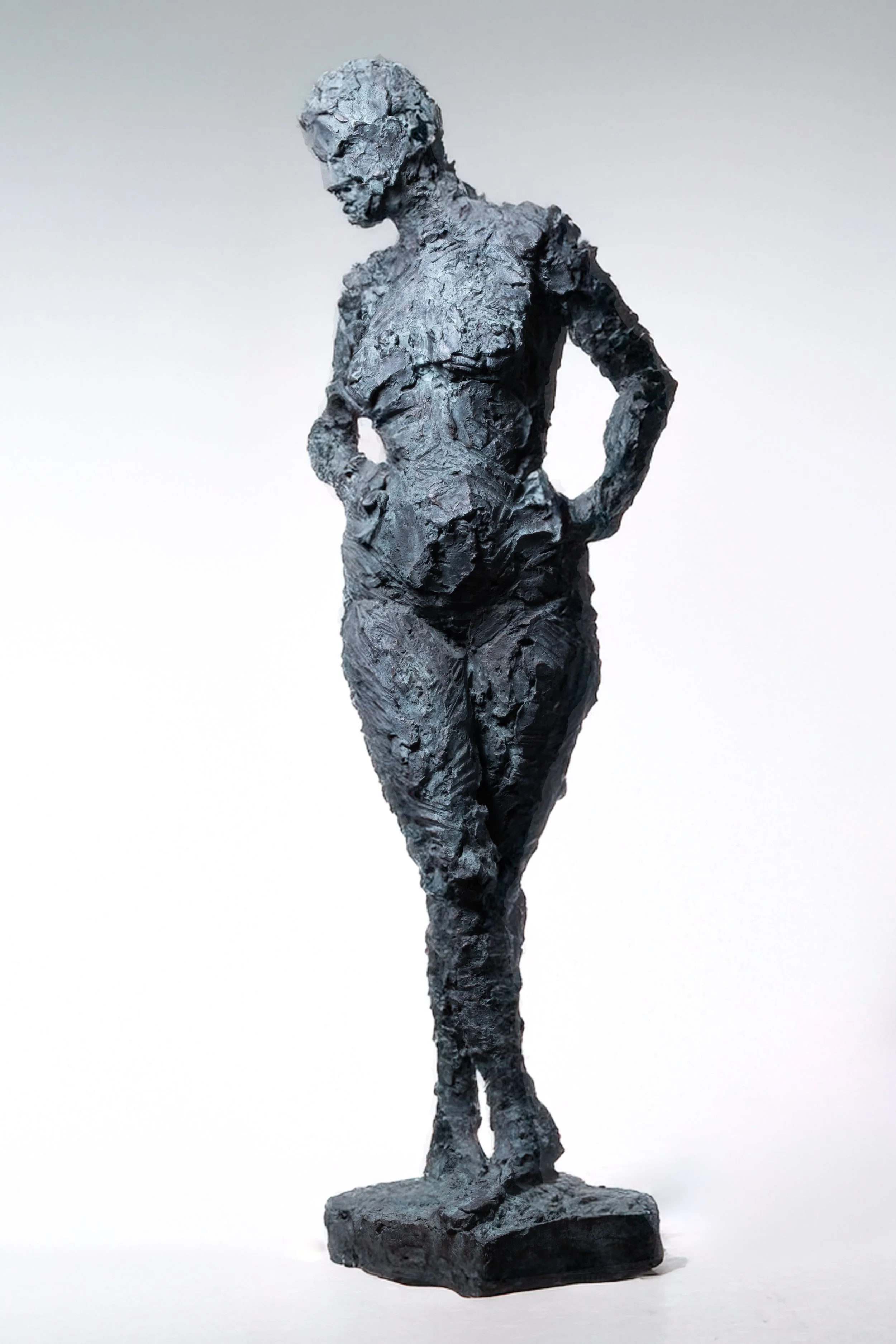 Eine strukturierte schwarze Skulptur einer Frau, die mit einer Hand in der Hüfte steht und den Kopf leicht gesenkt hat, vor einem schlichten hellen Hintergrund.