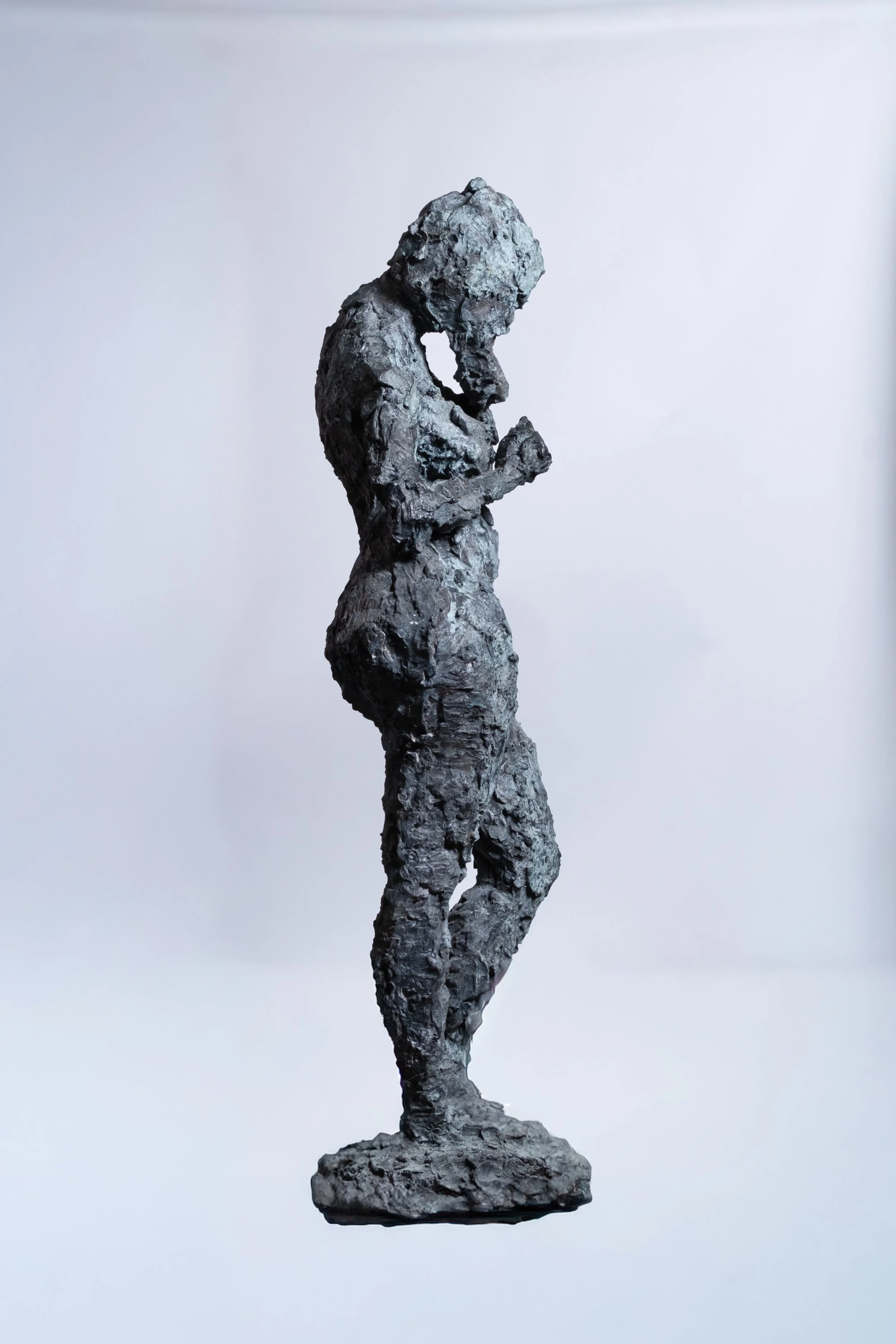 Eine strukturierte, metallische Skulptur einer im Profil stehenden Frau.