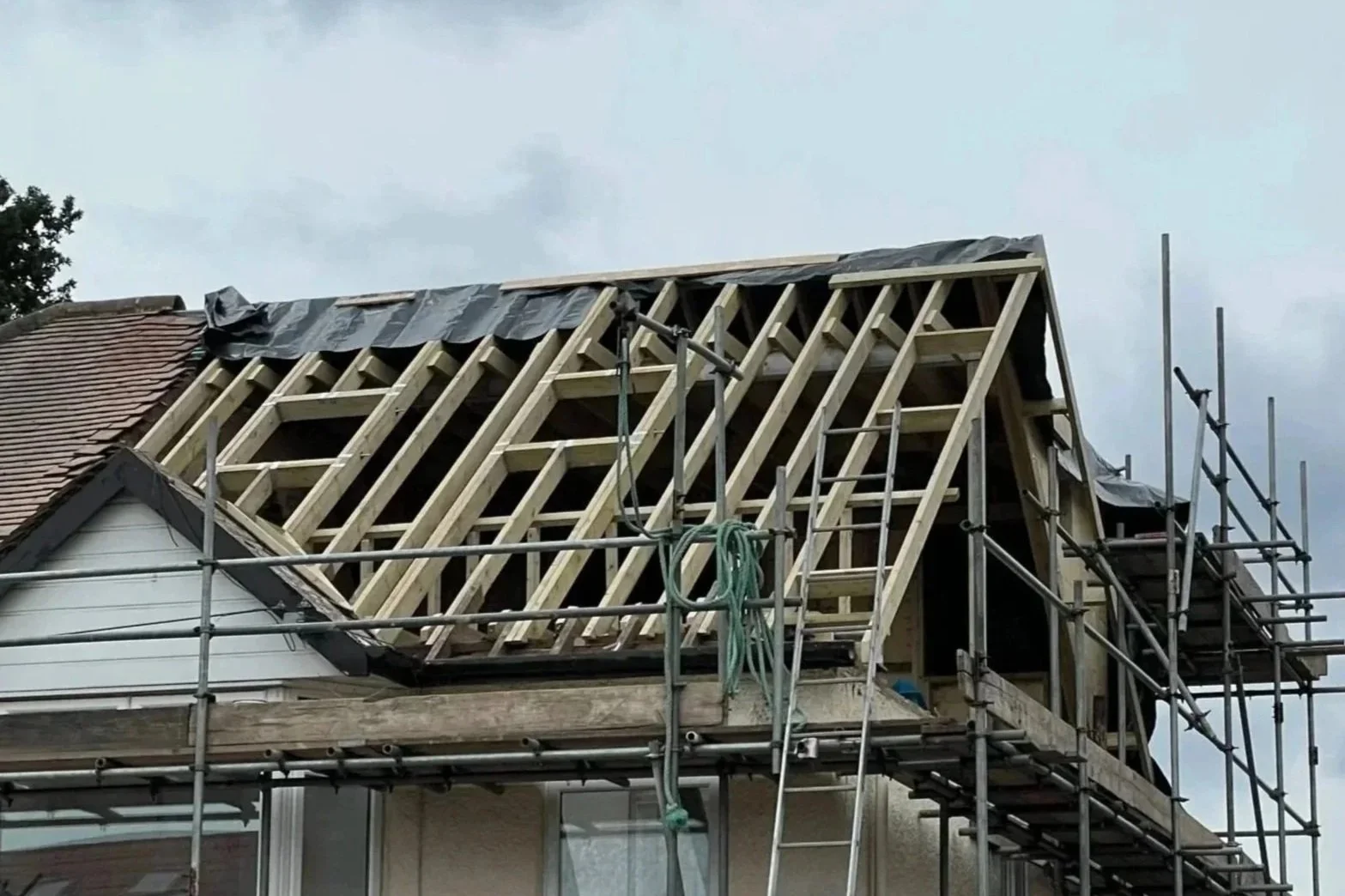 Construction of a house roof with wooden framework and scaffolding.