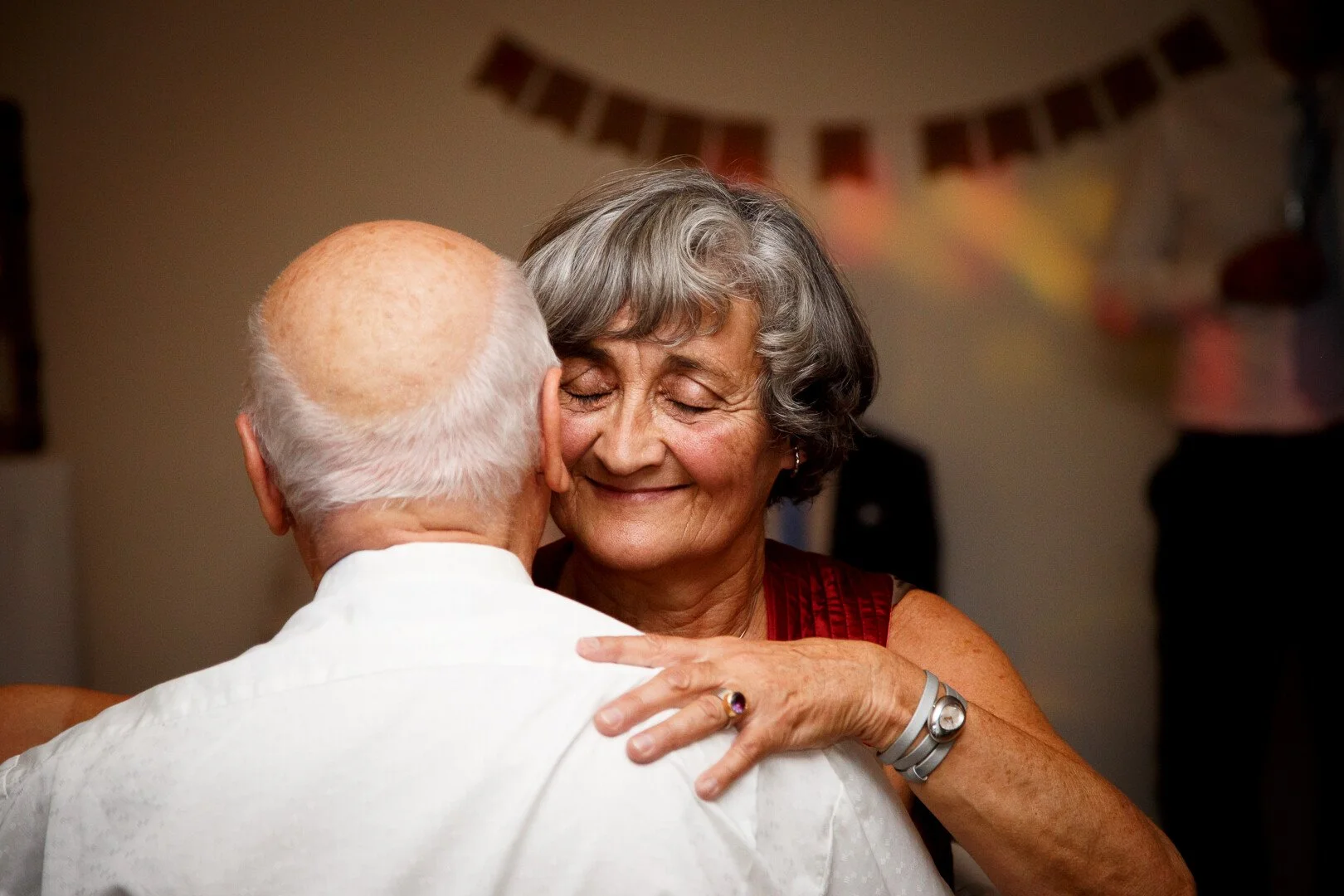 Älteres Paar beim Tango-Tanzen, lächelnd, in einer festlichen Umgebung mit bunten Dekorationen.
