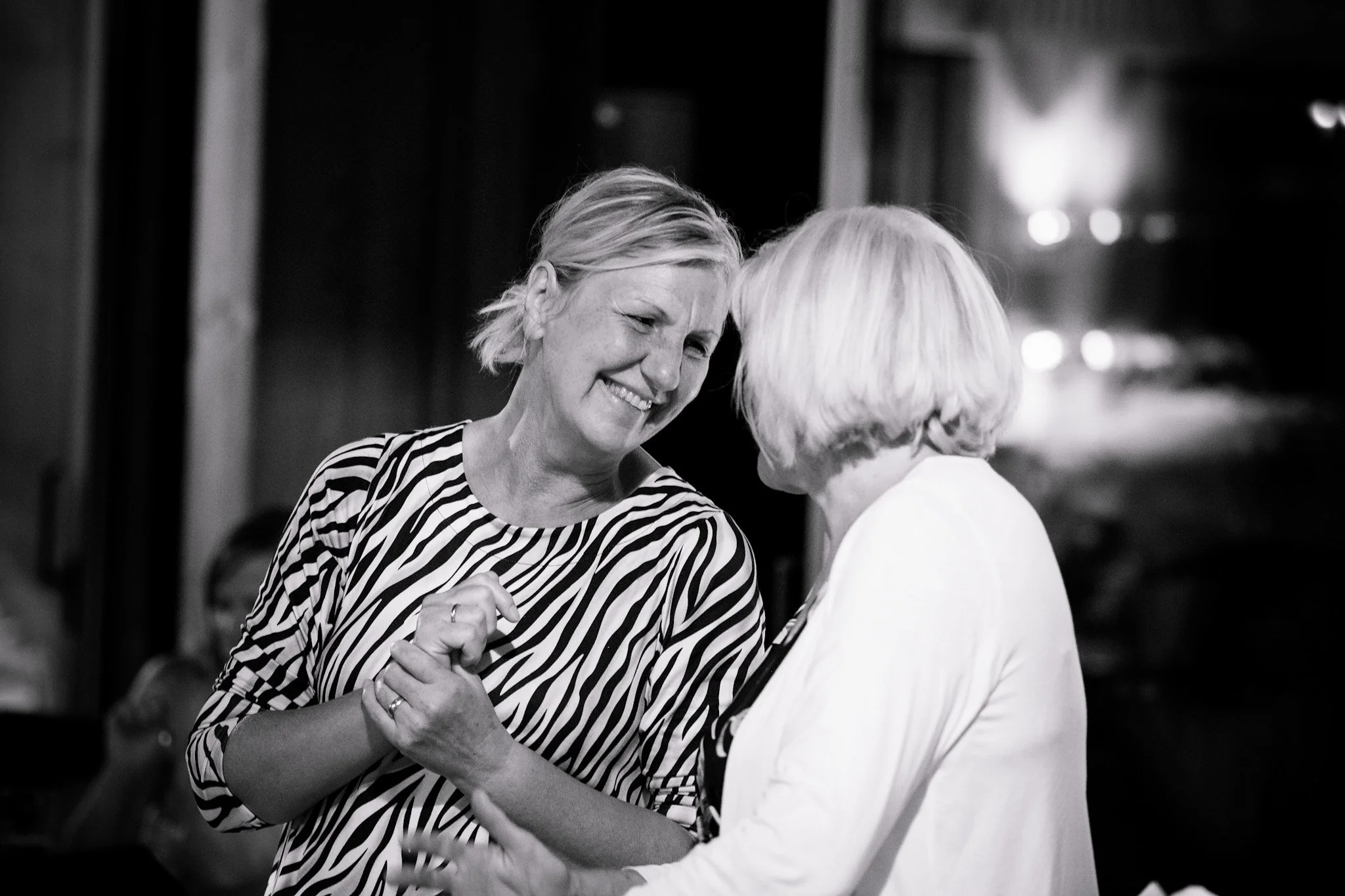 Zwei Frauen tanzen eng umschlungen und lachen.