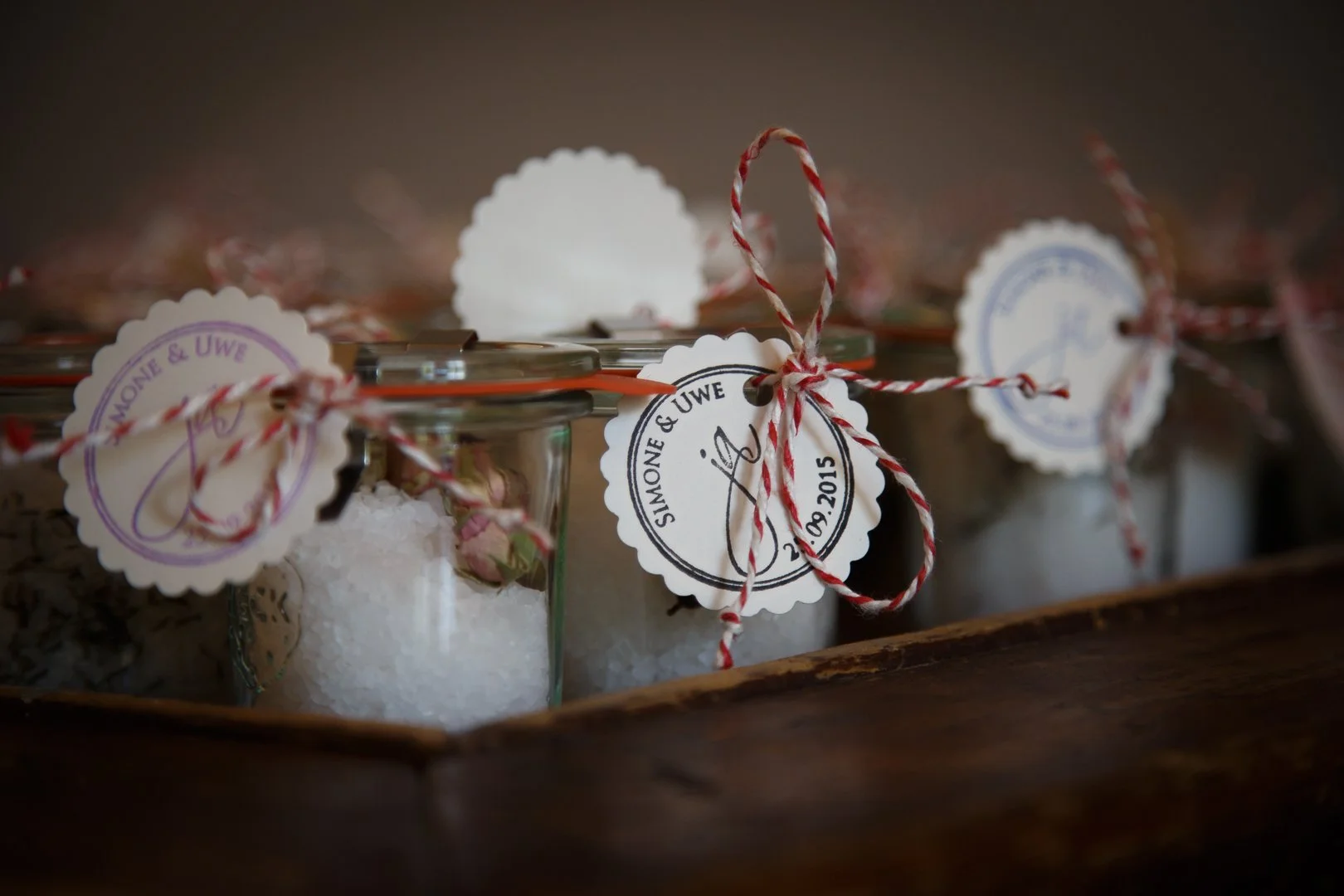 Gläser mit Salz und Blumen, verziert mit roter und weißer Schnur, mit handschriftlichen Etiketten, in einer Holzkiste