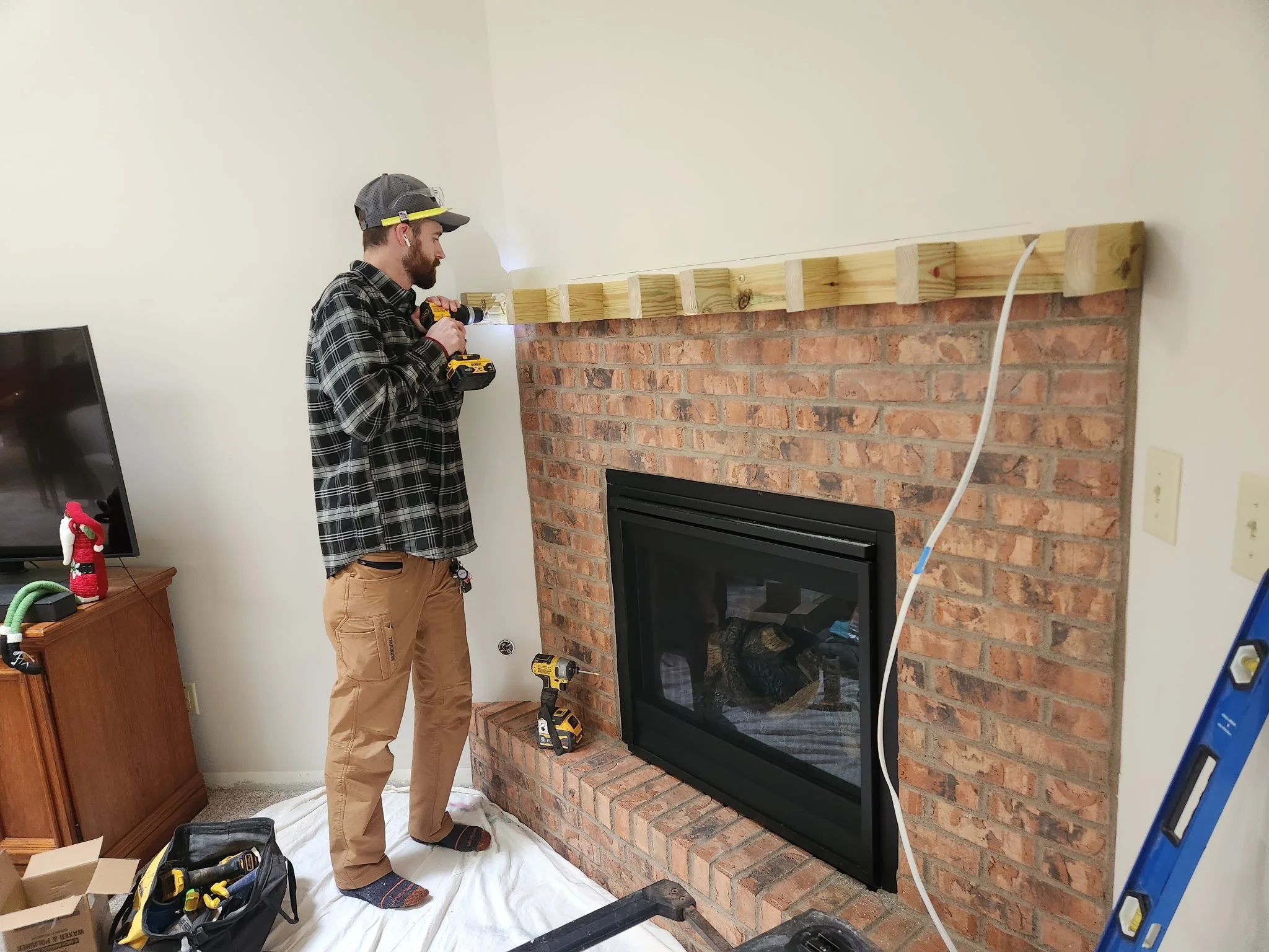 A man in a plaid shirt, tan pants, and a gray cap using a power drill on a wooden beam above a brick fireplace.


Installed near Centerville Ohio 