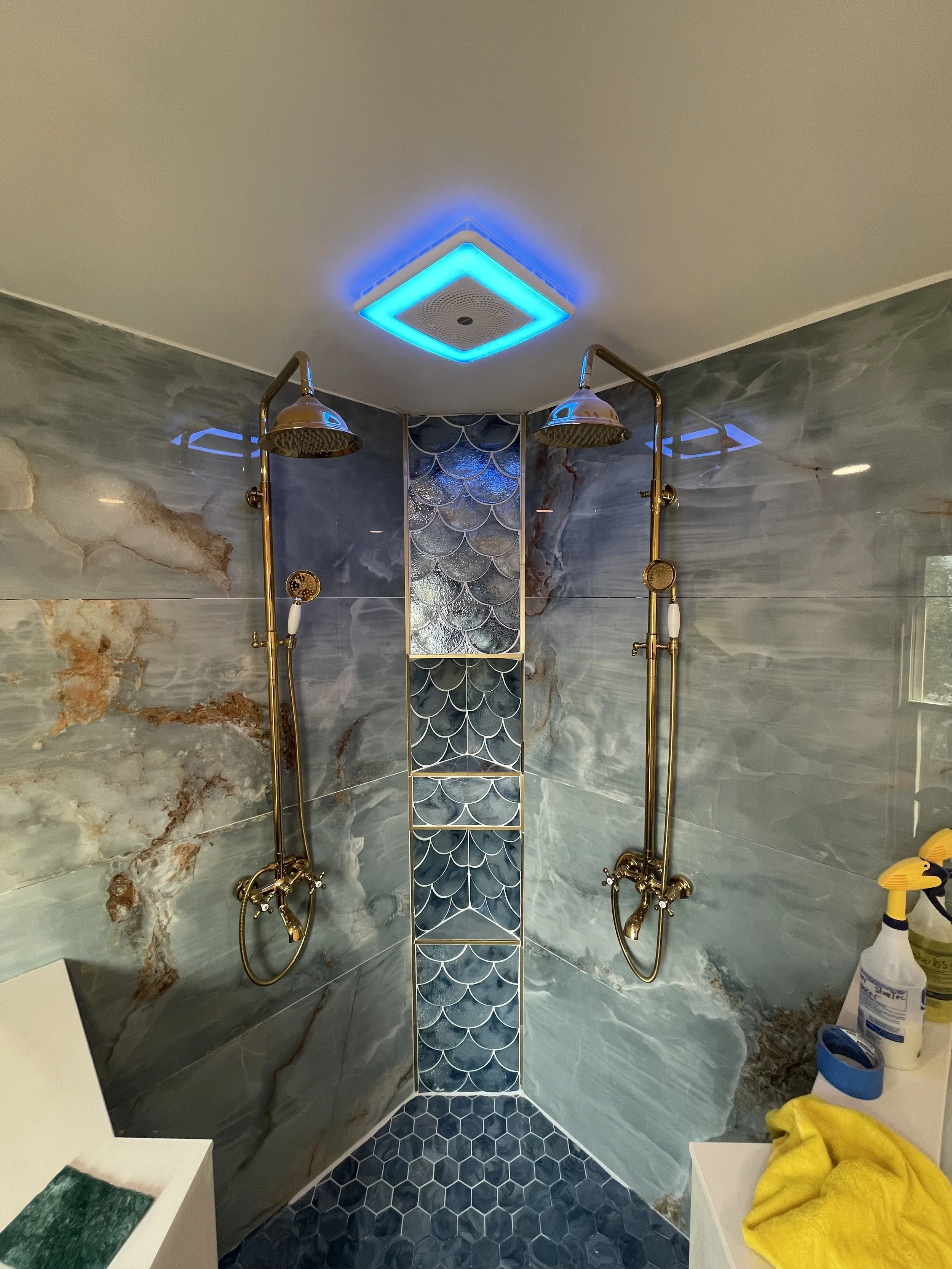 A walk-in shower with marble walls, blue fish scale tiles, and two gold shower heads.


Installed near west Alexandria Ohio