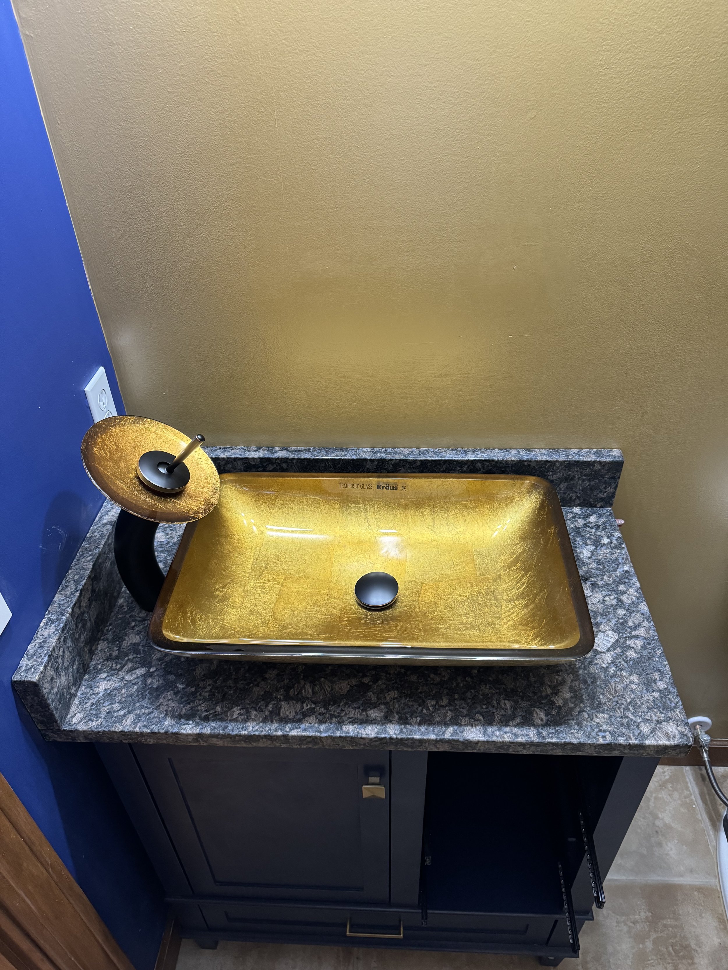 Golden sink with black faucet on a grey granite countertop, in front of a gold wall and blue wall with an electrical outlet.

Installed Near Eaton Ohio