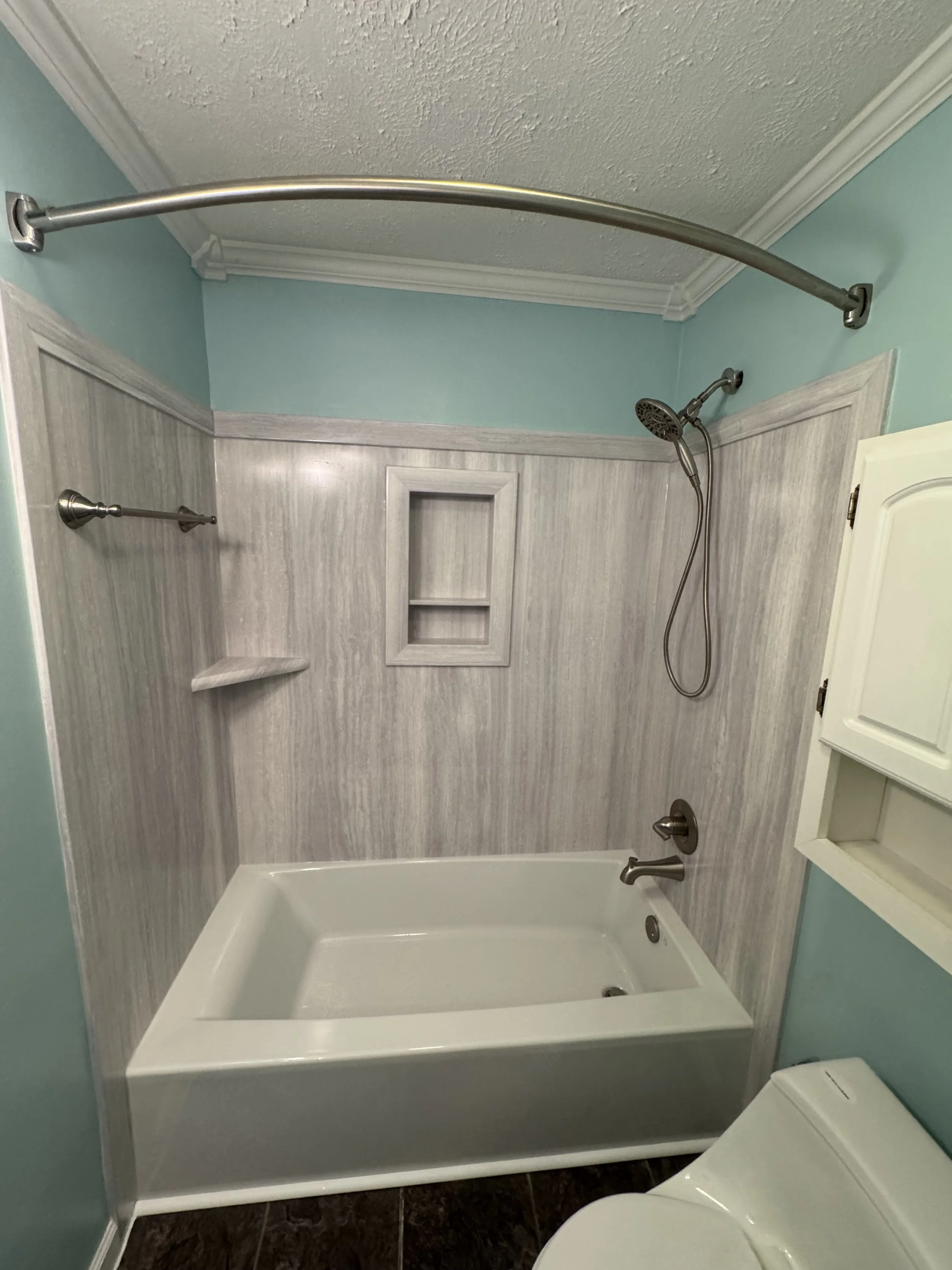 Bathroom with a bathtub, showerhead, blue walls, and a shower curtain rod.