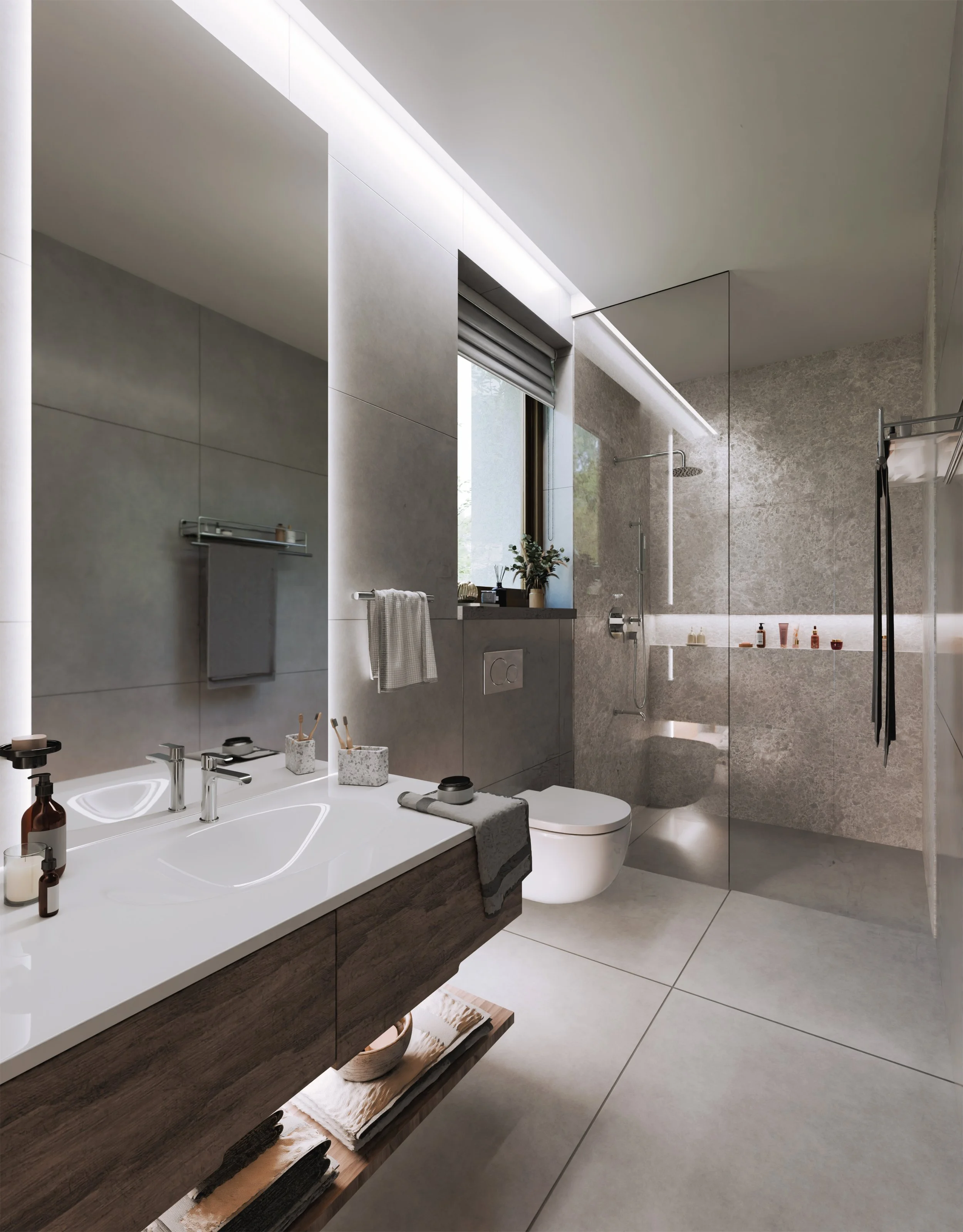 Modern bathroom with gray tiled walls and floor, a wall-mounted sink with a wooden cabinet, a mirror, a toilet, a window with a roller shade, a glass-walled shower area, and towels hanging on racks.