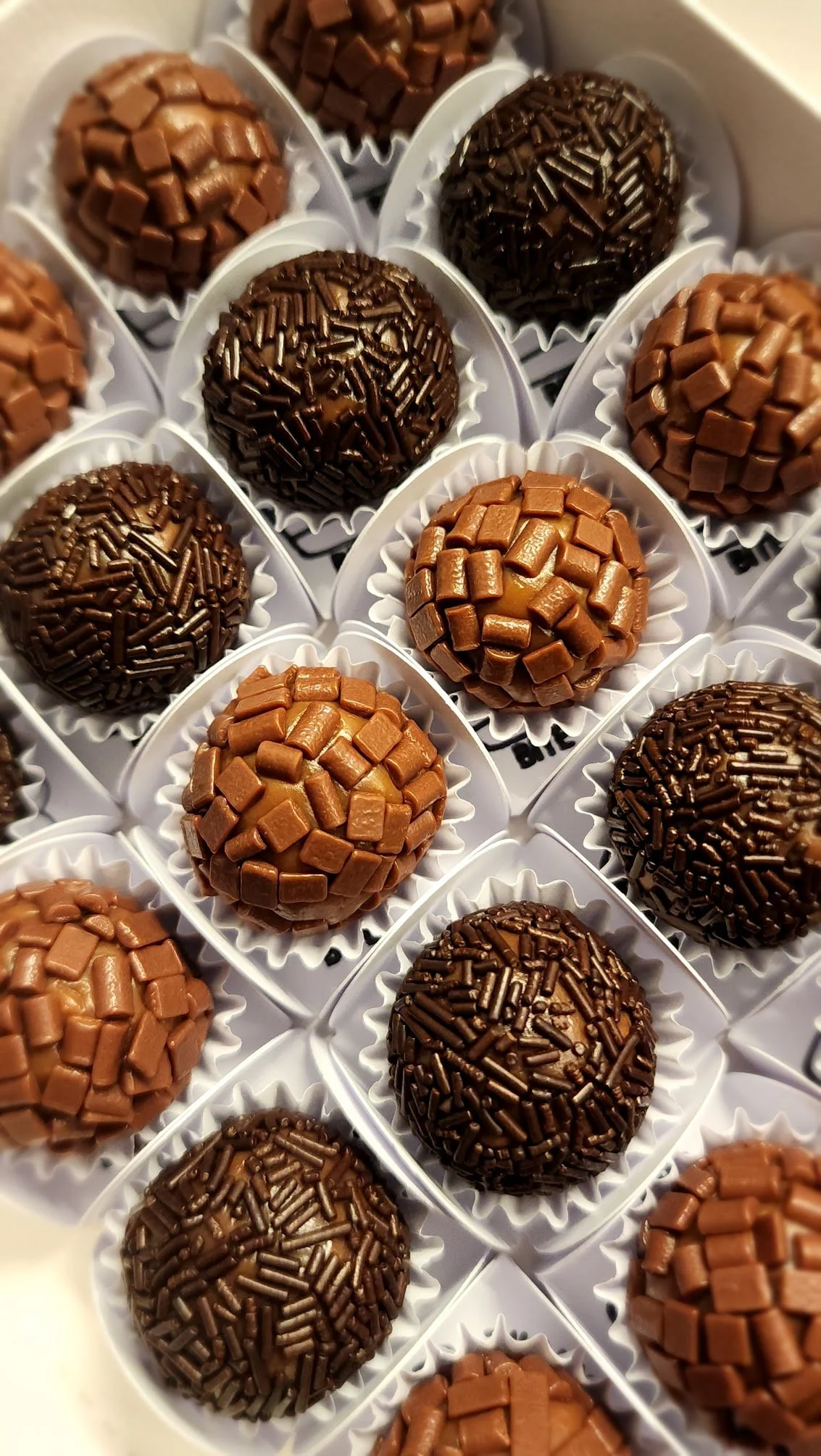 Assorted handcrafted Brazilian brigadeiros with classic and premium toppings, arranged for event service.