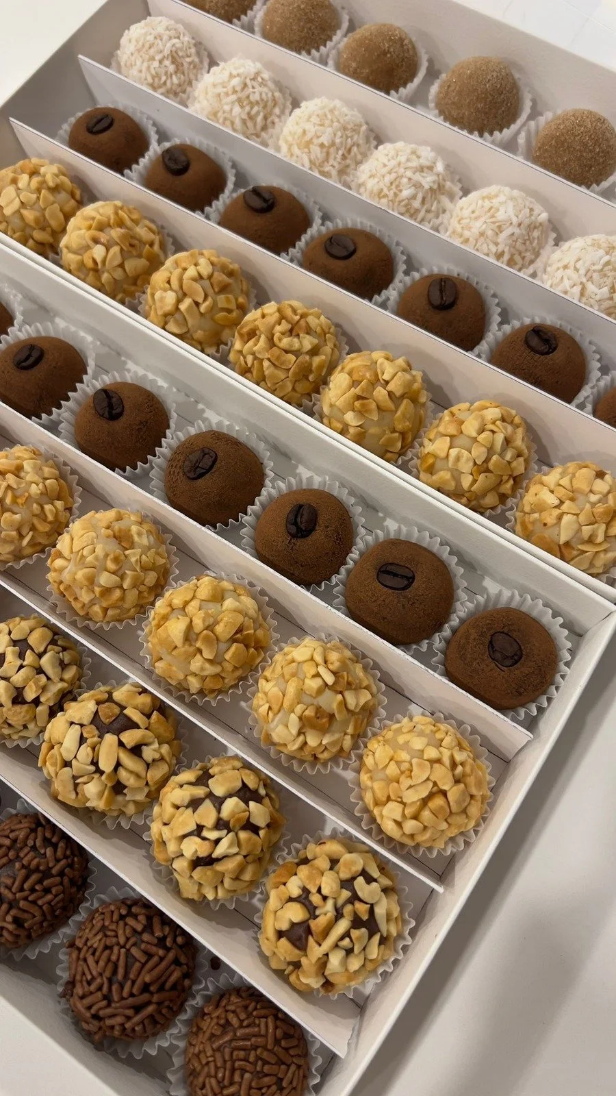 Assorted Brazilian brigadeiros with premium toppings, arranged in an elegant gift box.