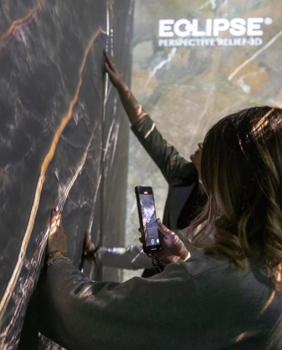 A woman is taking a photo of a person climbing a textured wall with the word 'ECLIPSE' and additional text in the background.