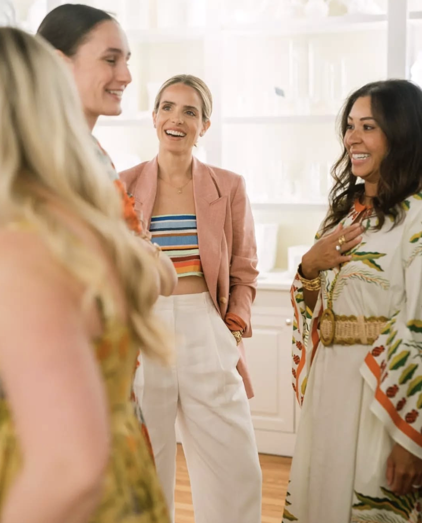 Group of women smiling and engaging in conversation in a bright room.