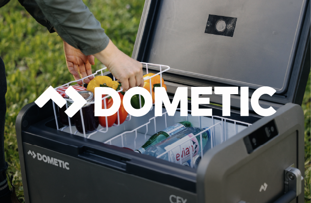 Person placing food items into a Dometic portable cooler outside.