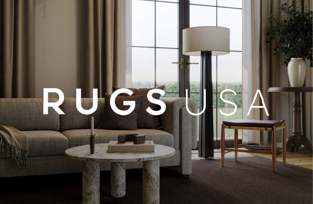Living room with sofa, coffee table, lamp, and large window with curtains, featuring the text 'RUGS USA' overlaid.