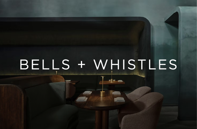 Cozy restaurant interior with a table set with napkins and gold candle holders, featuring a curved wall and ambient lighting, with the text 'Bells + Whistles' overlayed.