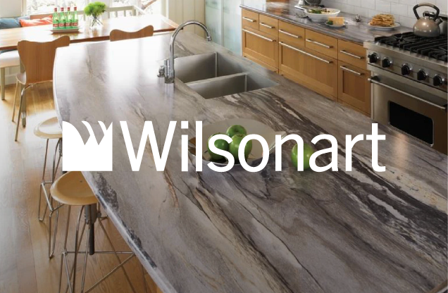 Kitchen with marble countertop island, sink, wooden cabinetry, stove, and green apples on the counter.