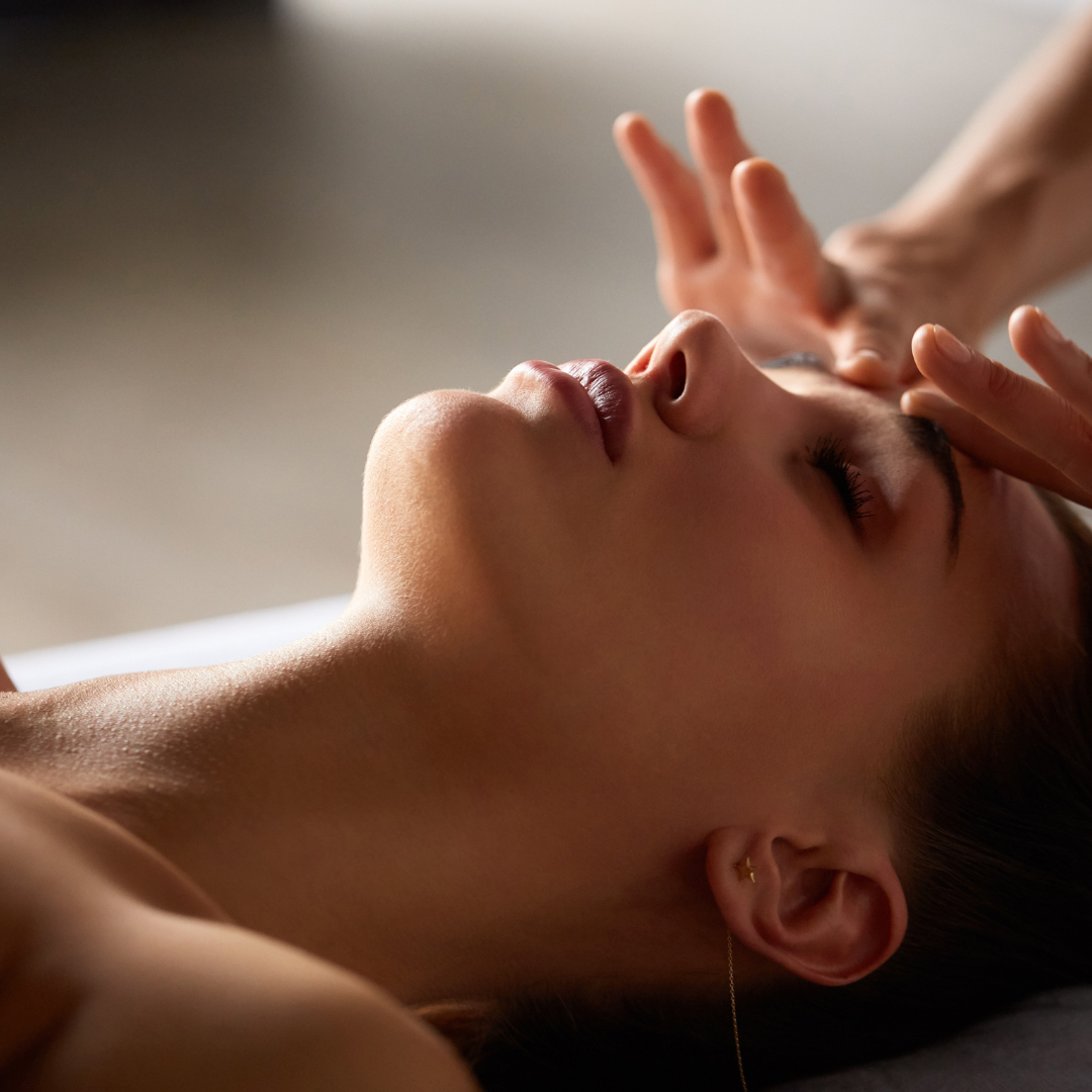 Close-up of a woman receiving a massage, with her eyes closed and peaceful expression.