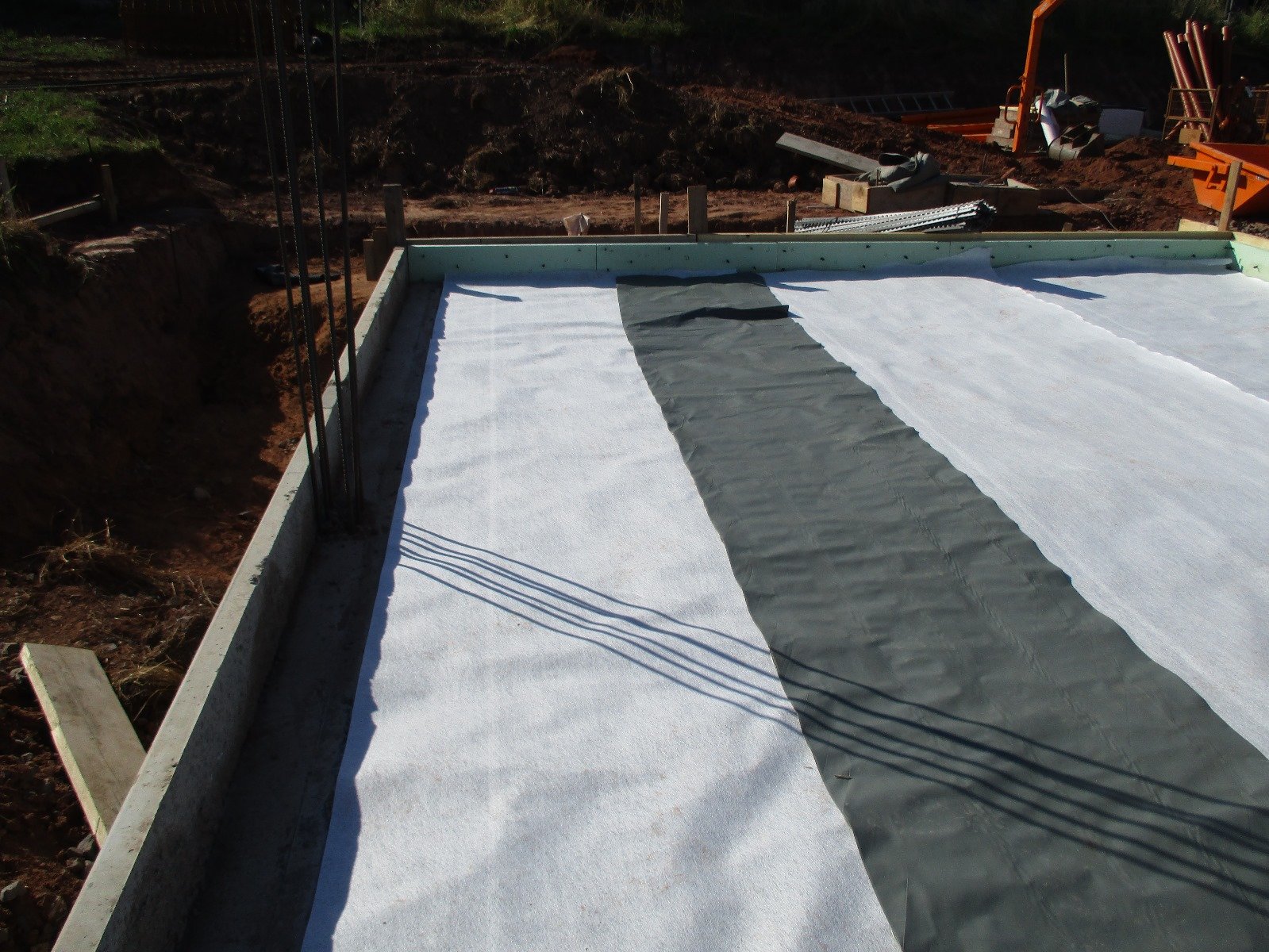 Fundament eines Gebäudes mit Isolierung und Bewehrungsstahl auf einer Baustelle.