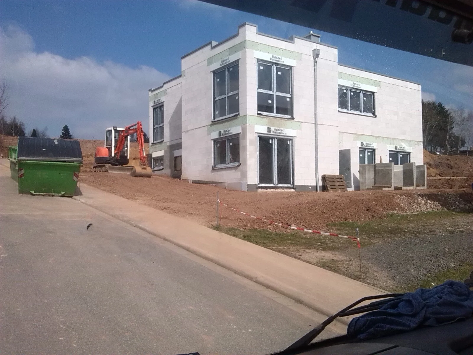 Bau eines mehrstöckigen Hauses auf einer Baustelle mit Baumaschinen und Baumaterialien.