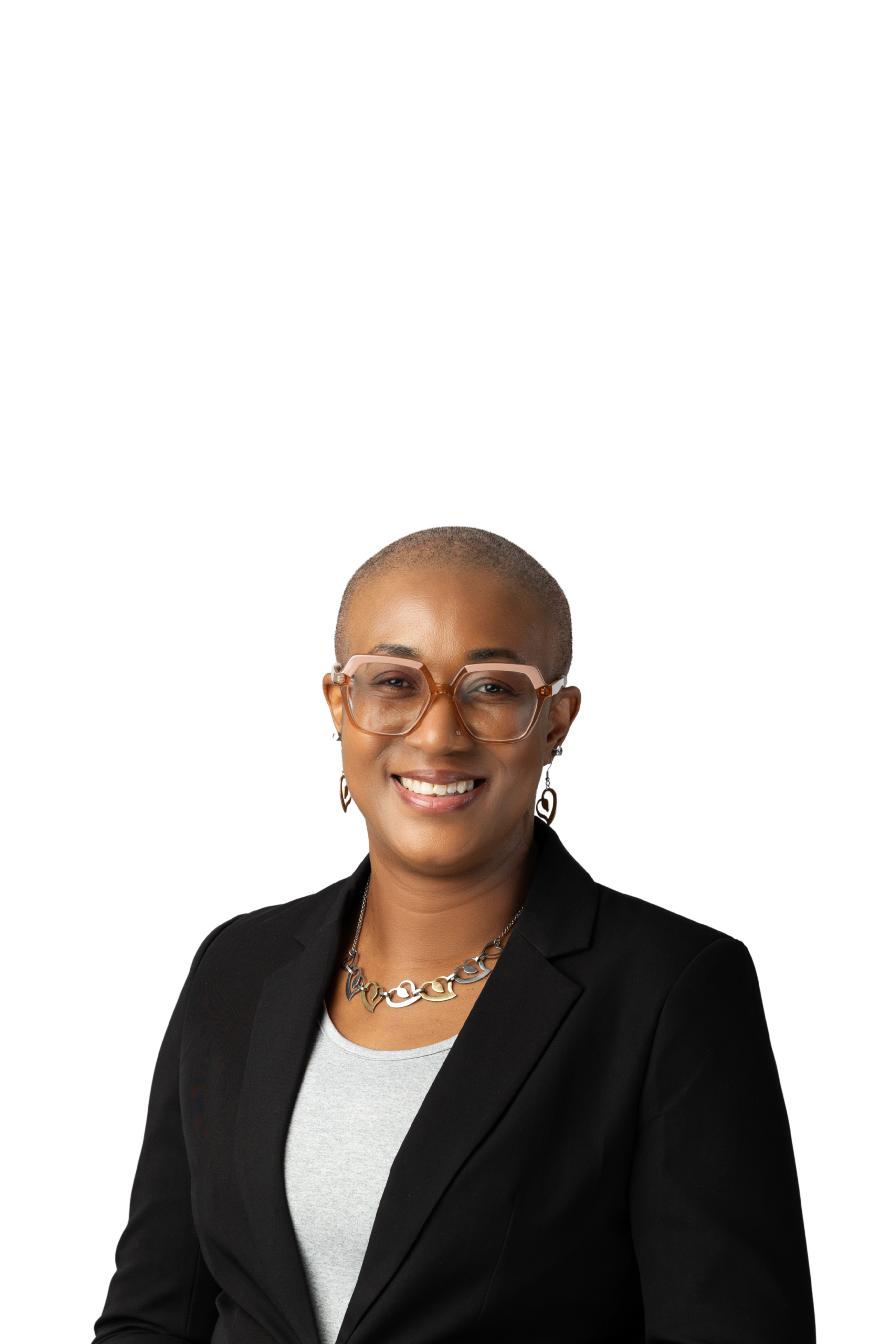 Tamica Daley, Career Advisor and Author, with a bald head, wearing glasses, a black blazer, a grey shirt, a gold necklace, and earrings, smiling confidently against a plain background.