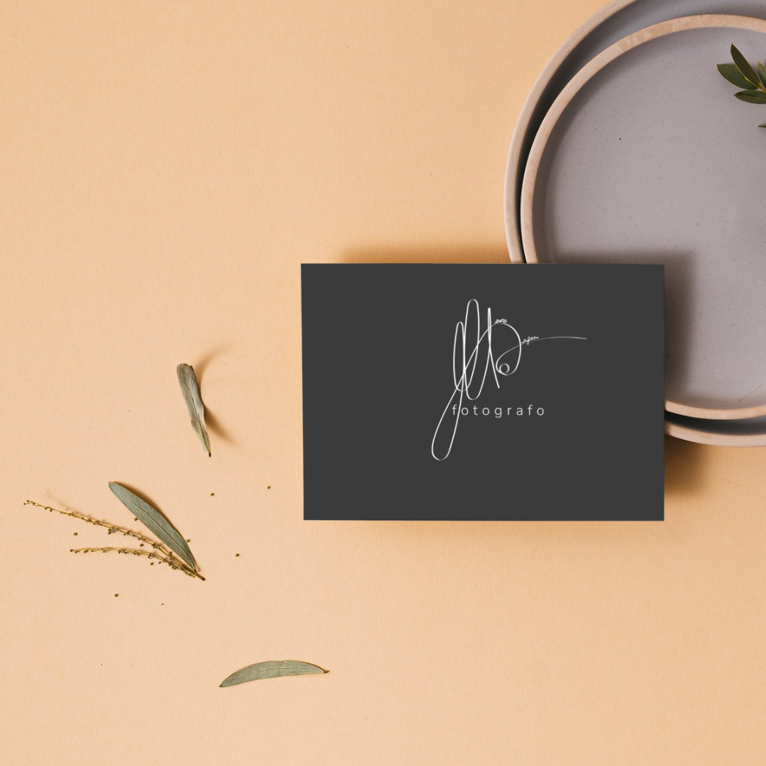 Carta e piatti di ceramica su uno sfondo beige, decorati con foglie verdi.