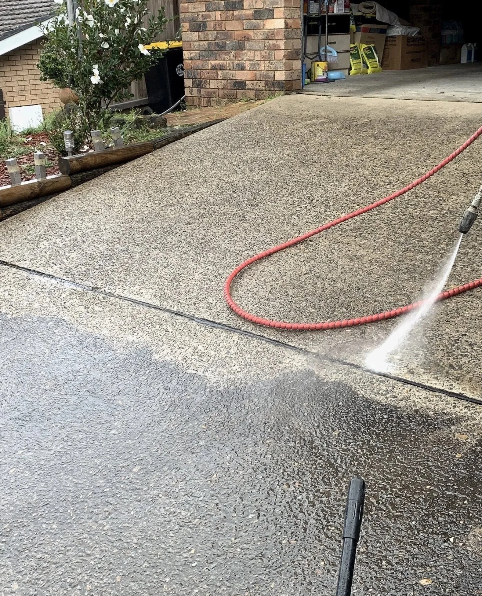 power washing a concrete driveway outside a house.