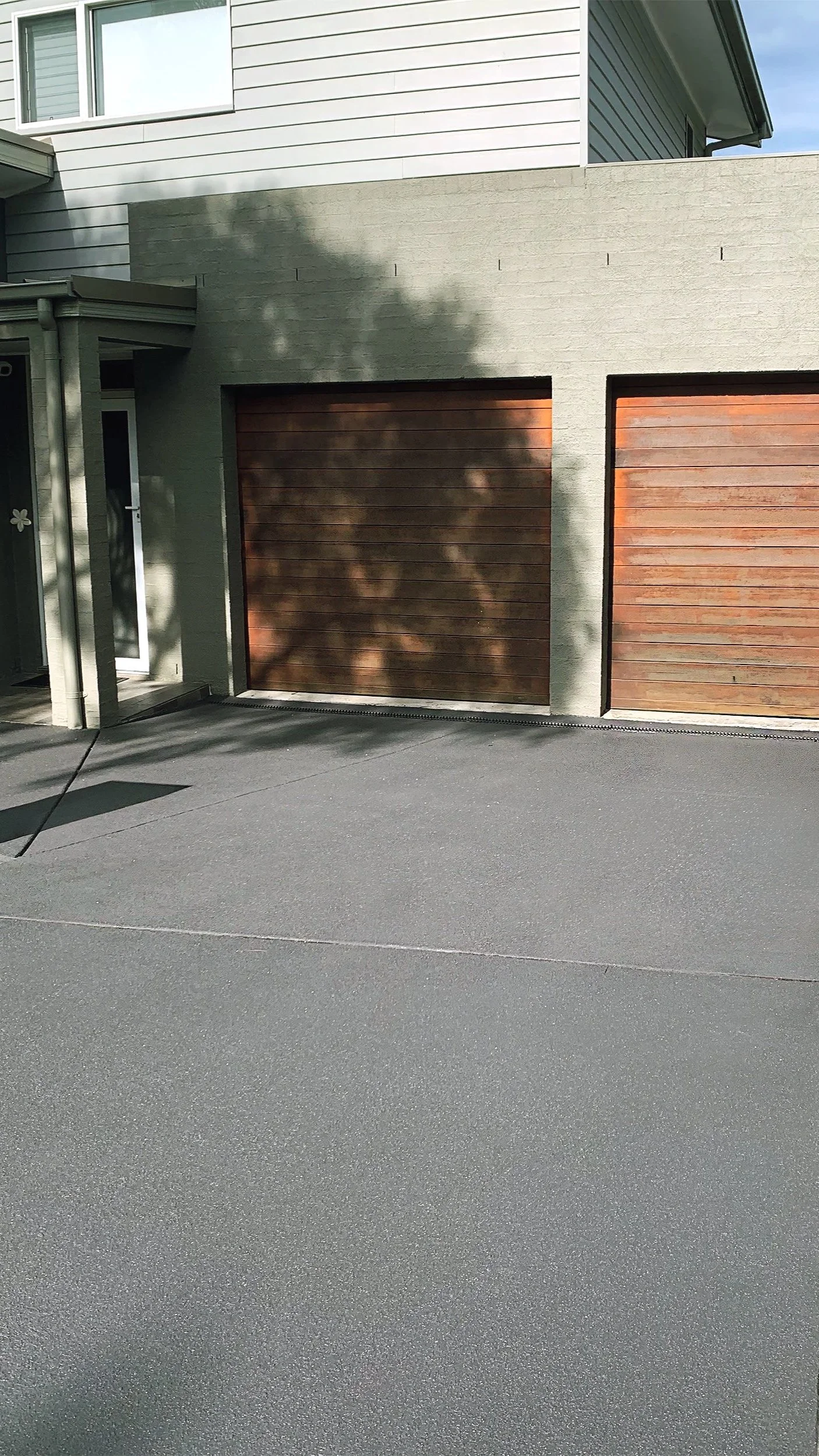 The Result: We completely transformed the entrance with a modern, dark charcoal resurfacing coat. This high-contrast finish provides a clean, professional aesthetic that perfectly complements the timber garage doors and modern exterior of the home.