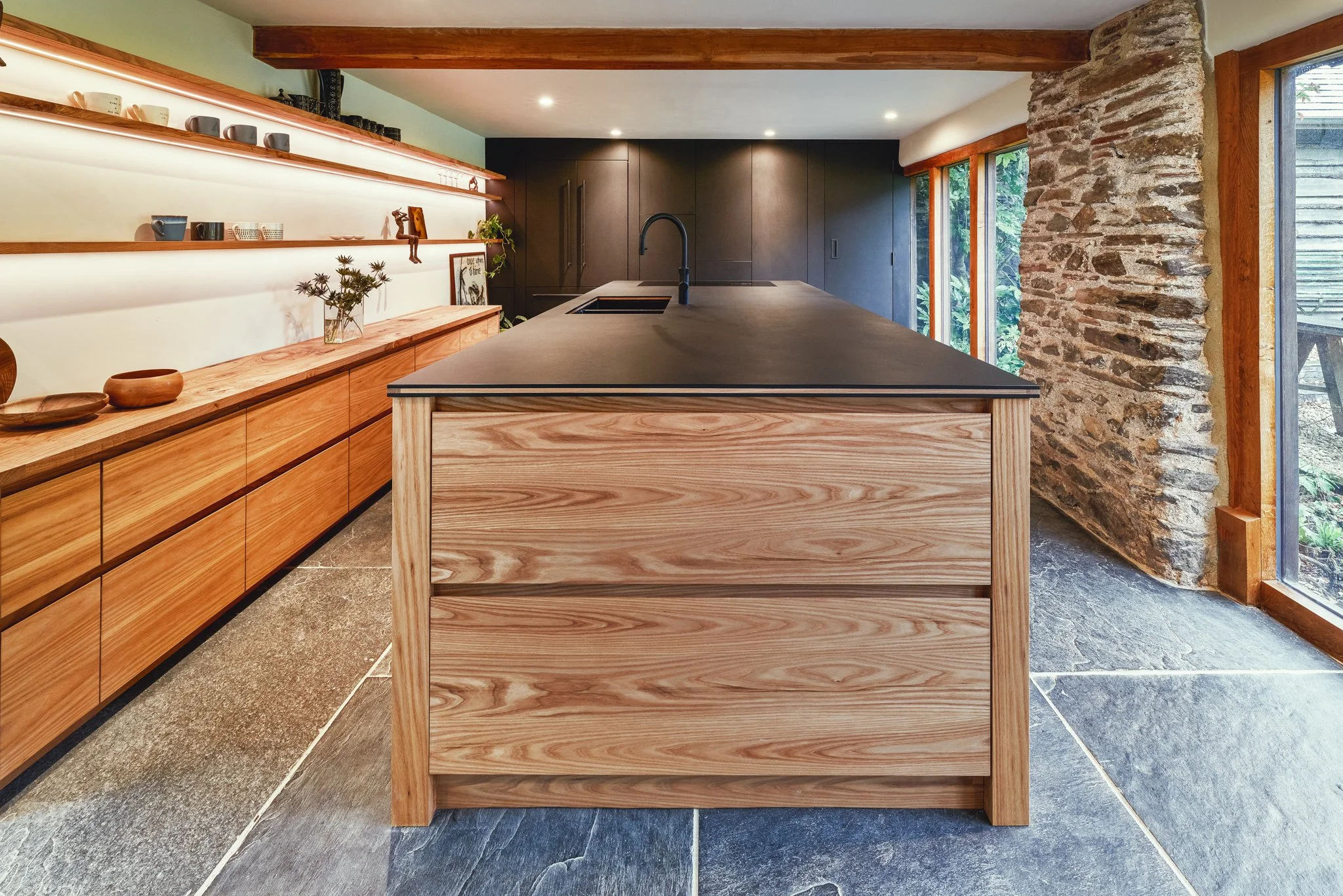 Bespoke elm kitchen with quality worktops and warm timber joinery in a Devon stone barn, Slapton