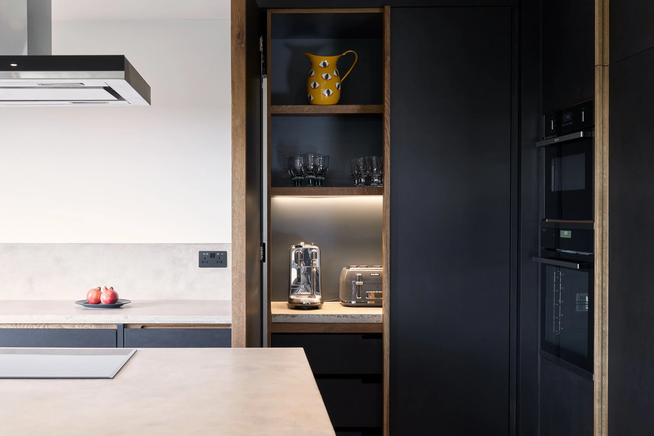 Bespoke dark black kitchen cabinetry with oak handles and hand-cast concrete worktops in Dartmouth, Devon