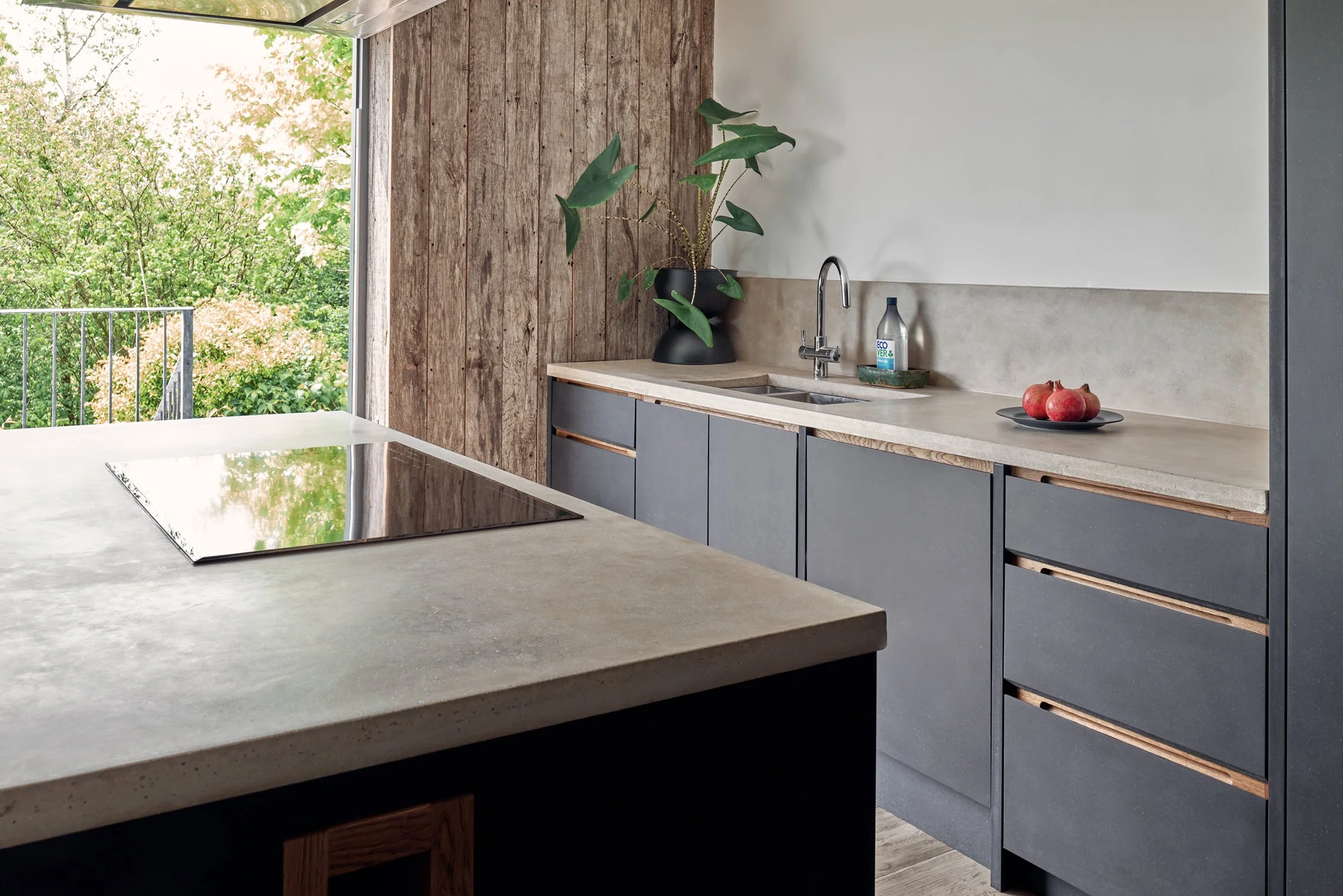 Bespoke dark black kitchen cabinetry with oak handles and hand-cast concrete worktops in Dartmouth, Devon