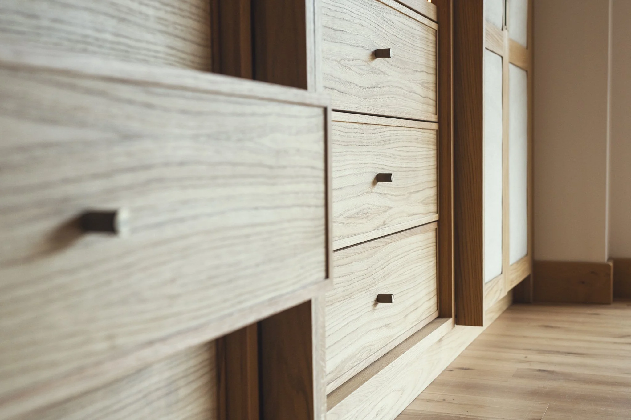 Luxury bespoke master dressing room wardrobes with pivot pocket doors and oak veneer in Dartmouth, Devon