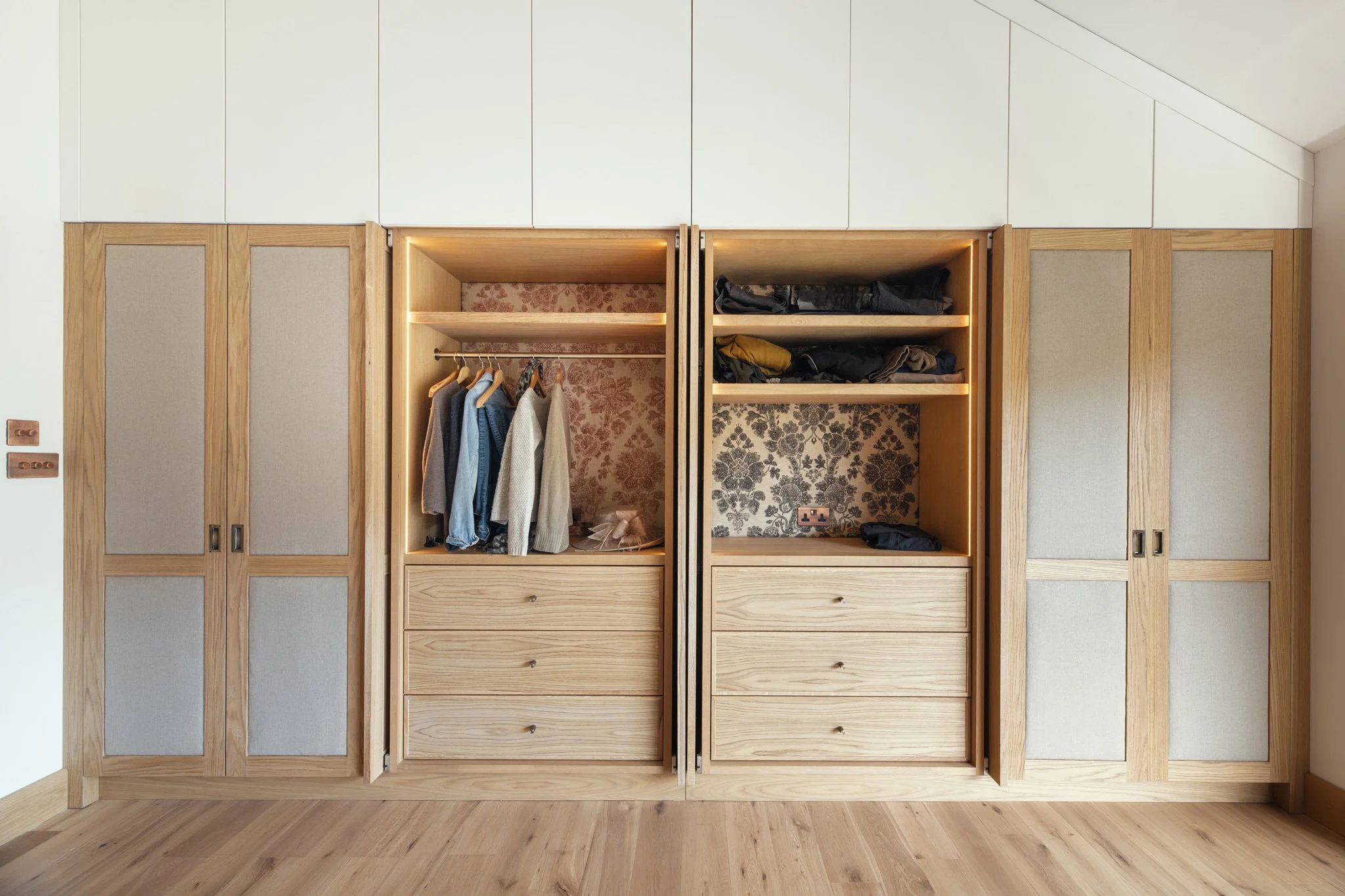 Luxury bespoke master dressing room wardrobes with pivot pocket doors and oak veneer in Dartmouth, Devon